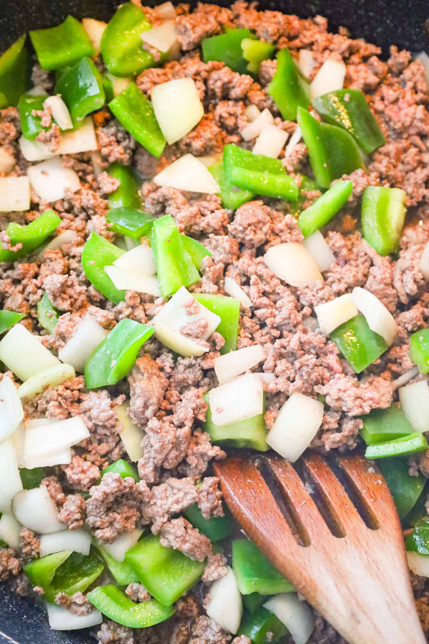 diced green peppers, diced onions and ground beef cooking in a saute pan