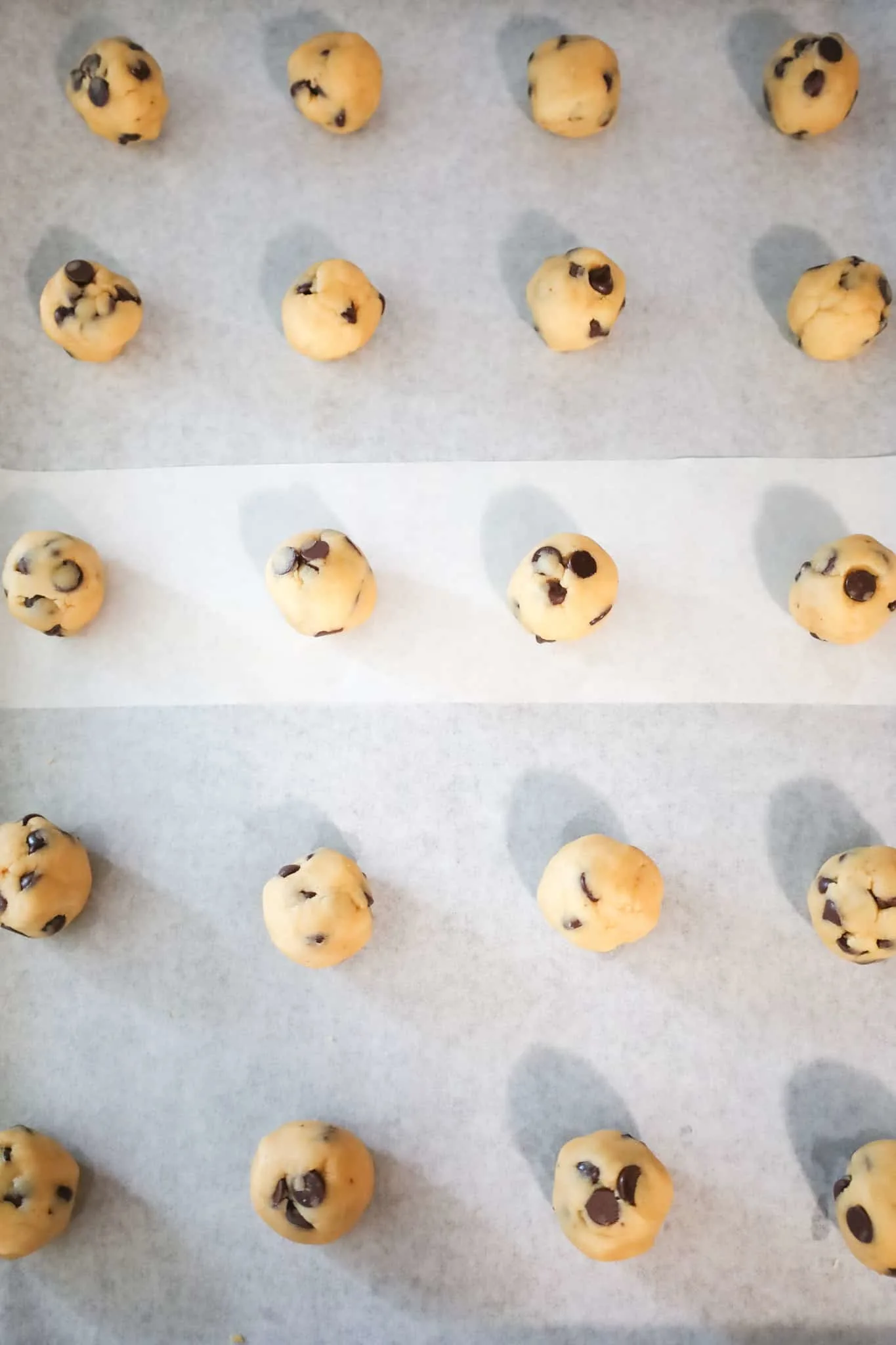 chocolate chip cookie dough balls on a parchment lined baking sheet