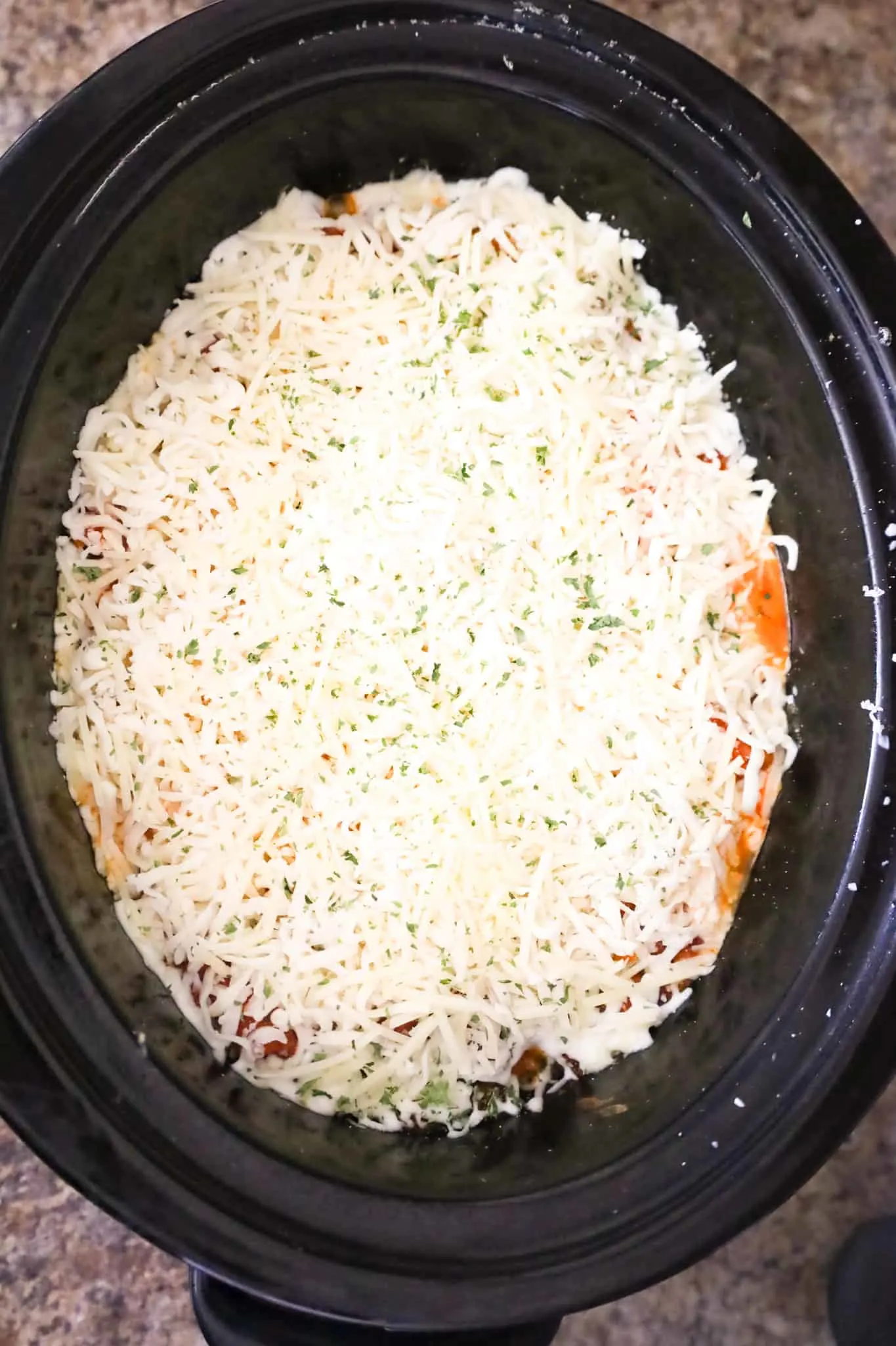 shredded cheese on top of ziti in a crock pot