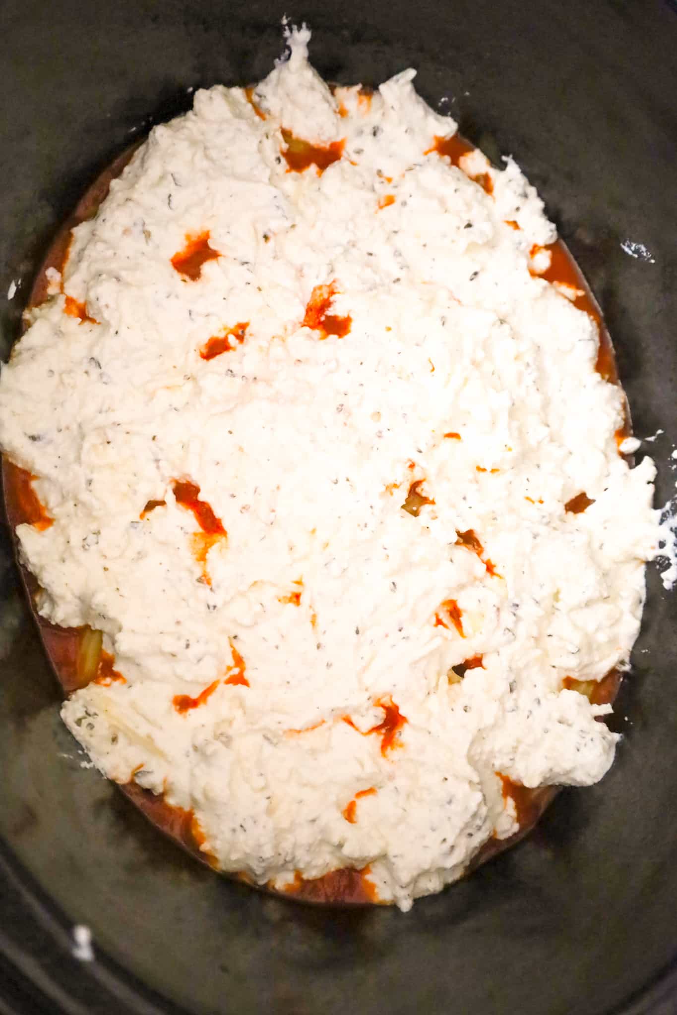 ricotta mixture on top of marinara and noodles in a crock pot