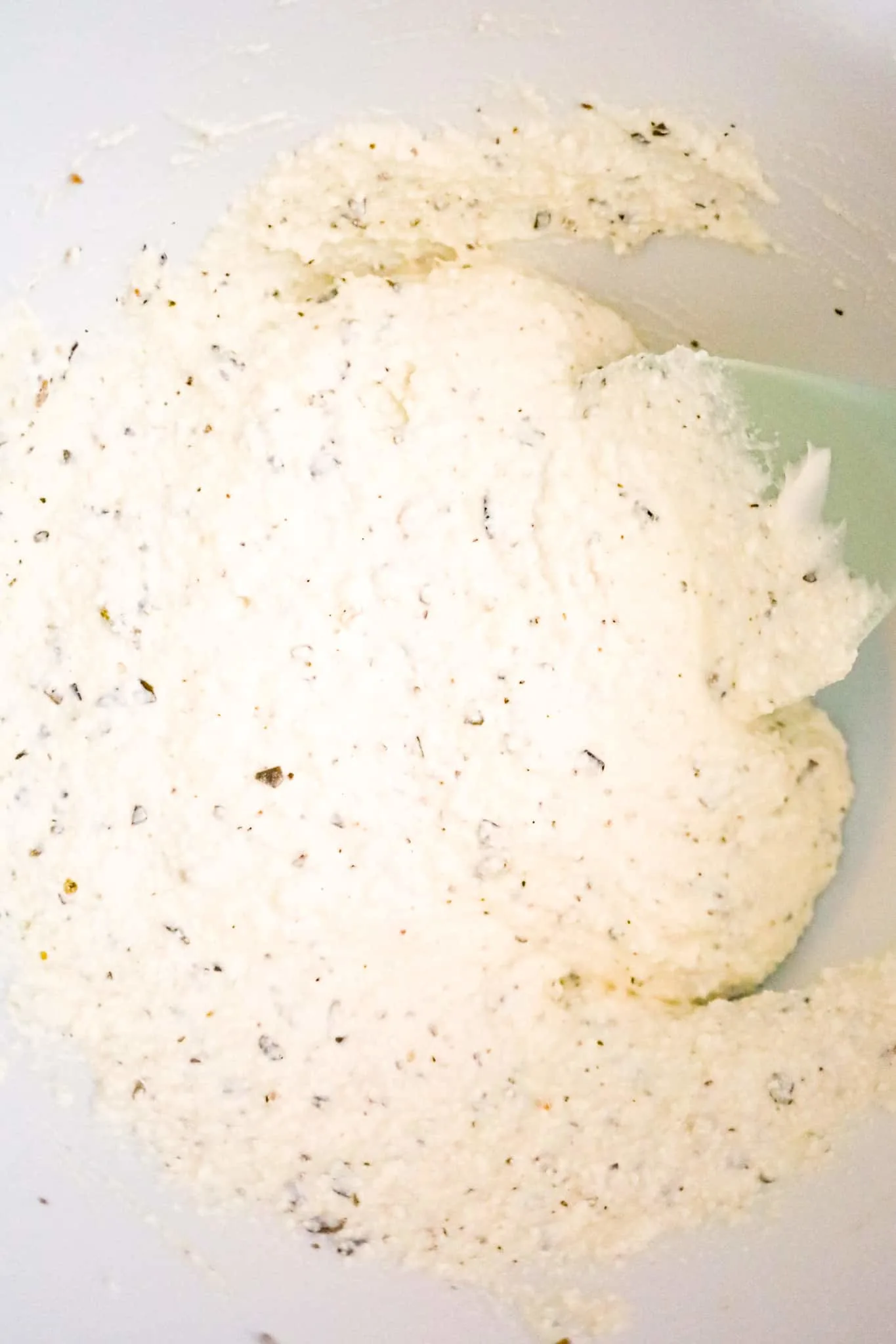 sour cream, ricotta cheese and basil pesto mixture in a mixing bowl