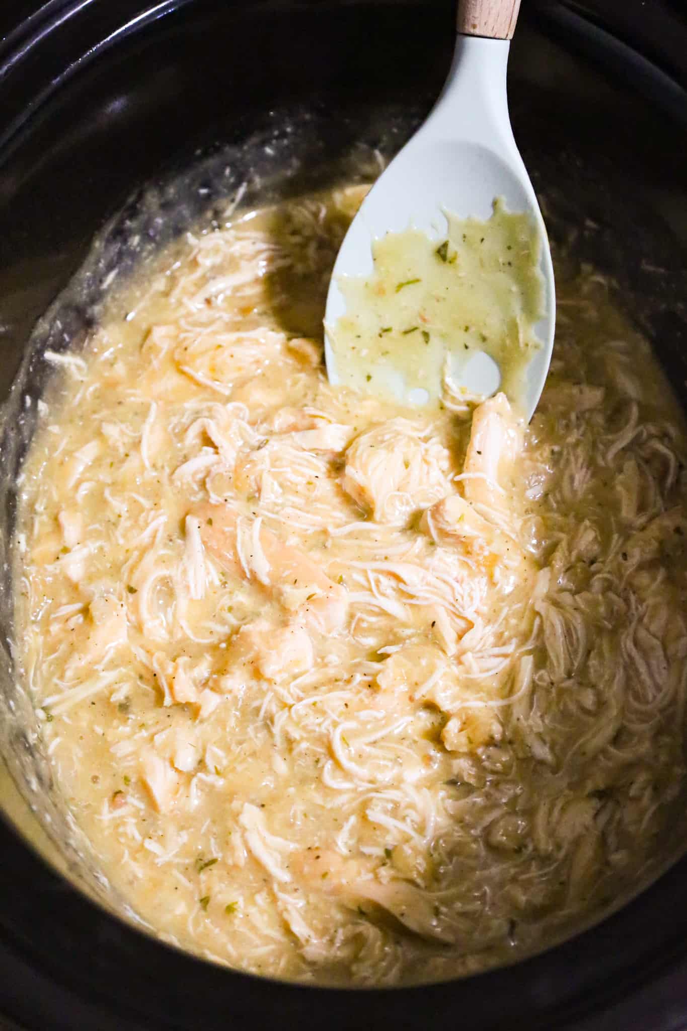 chicken and gravy being stirred in a crock pot