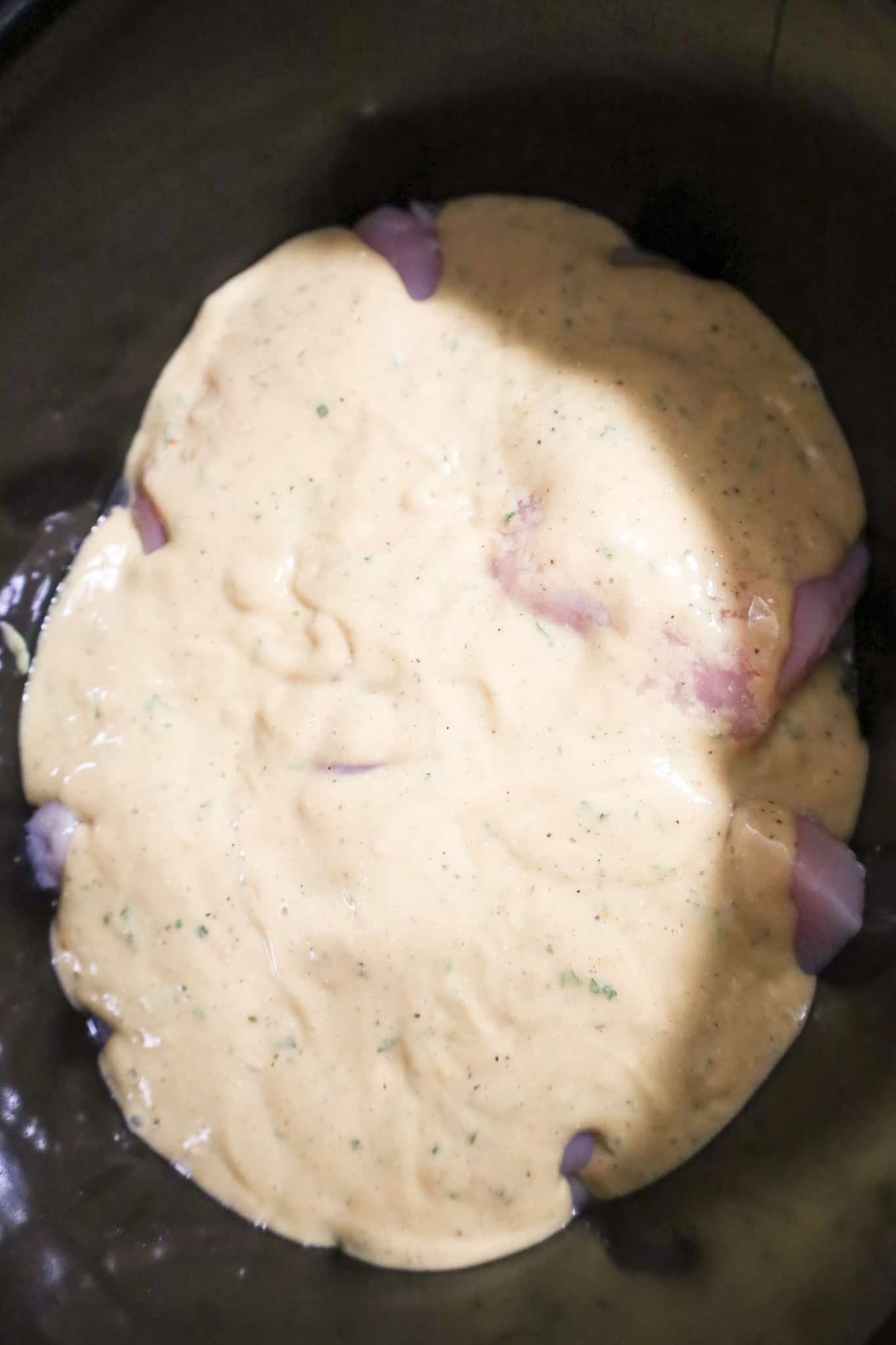 cream of chicken soup and gravy mixture on top of chicken breasts in a crock pot