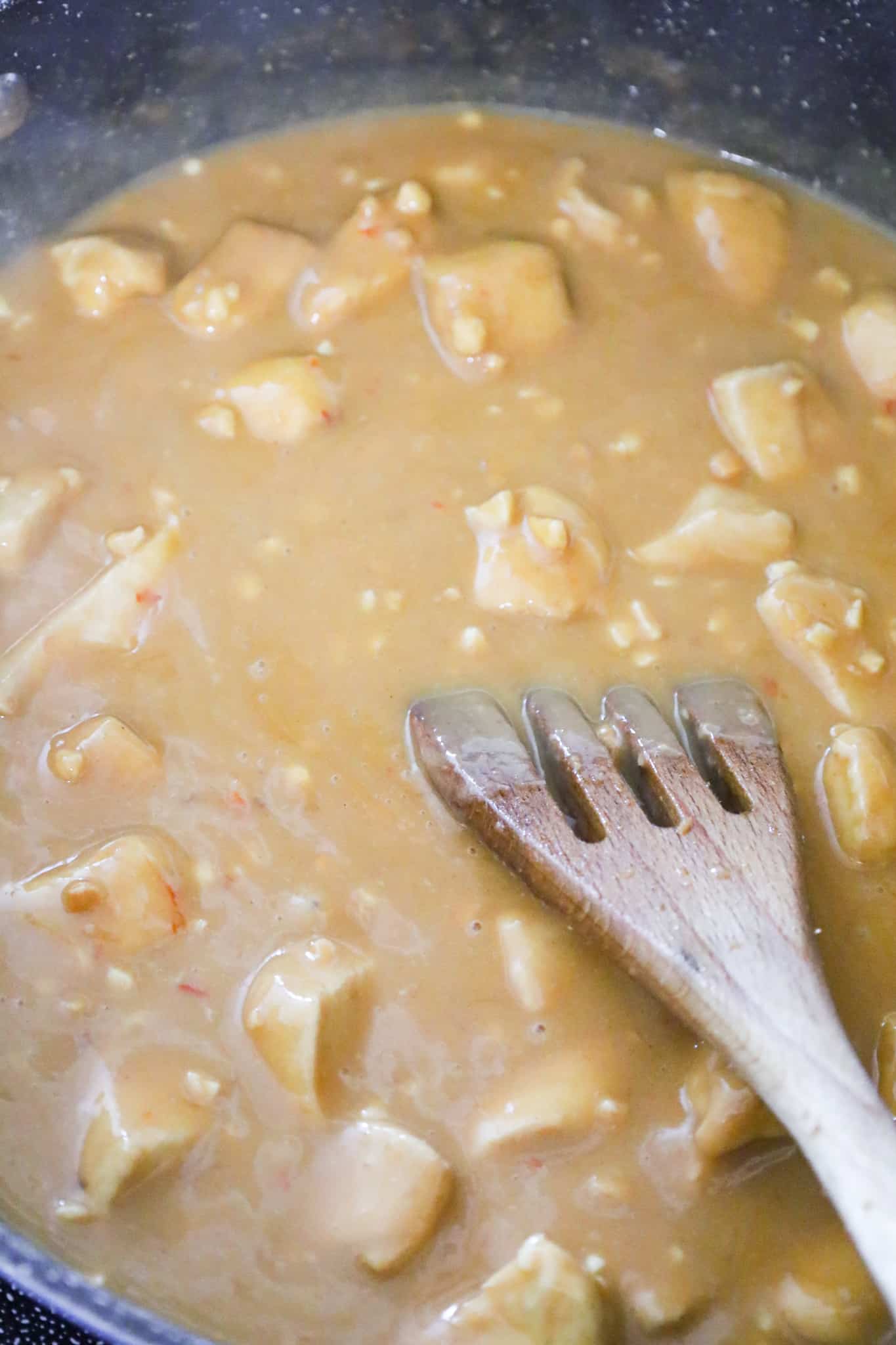 chicken breast chunks in peanut butter sauce in a saute pan