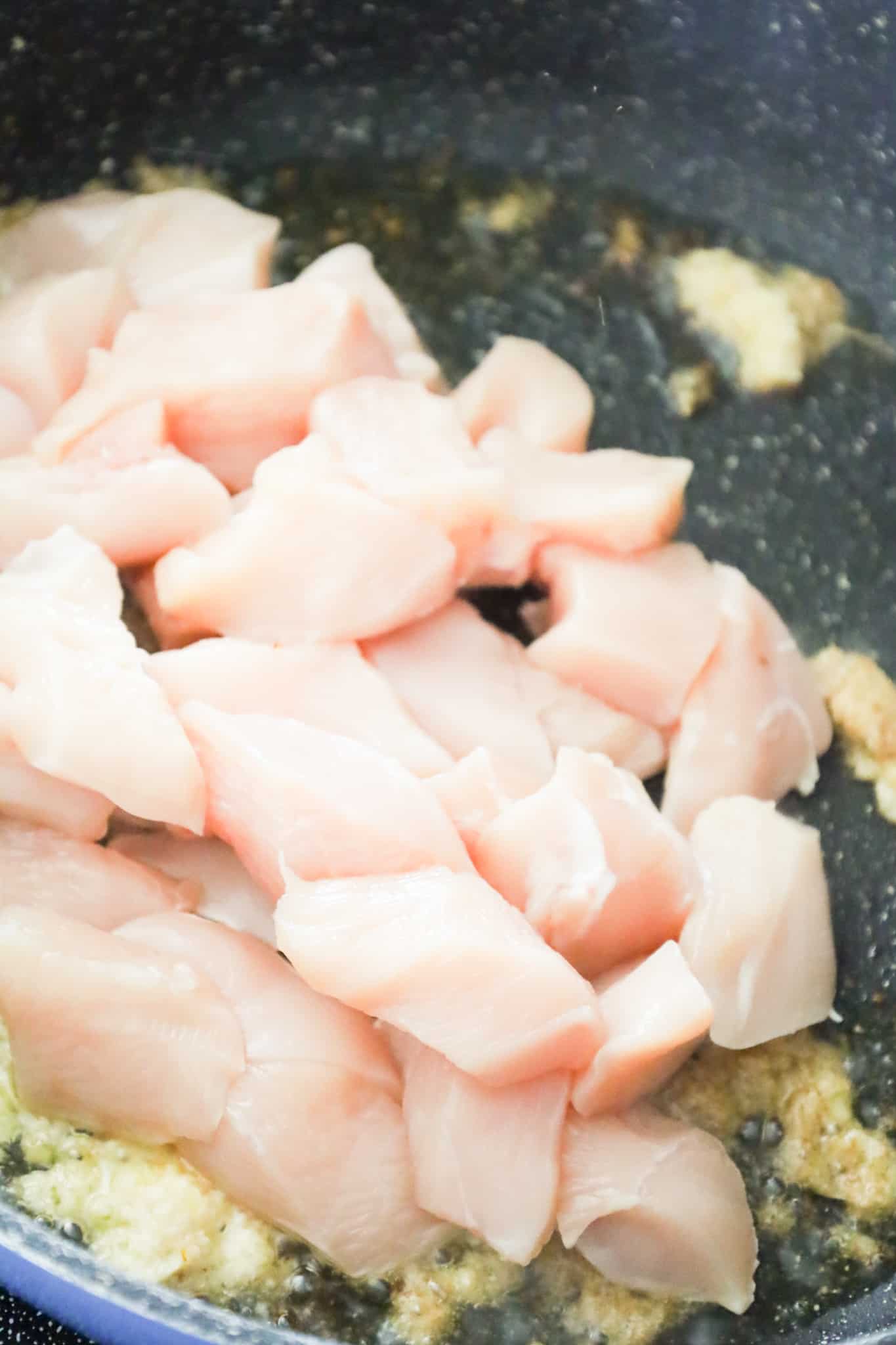 raw chicken breast chunks in a saute pan
