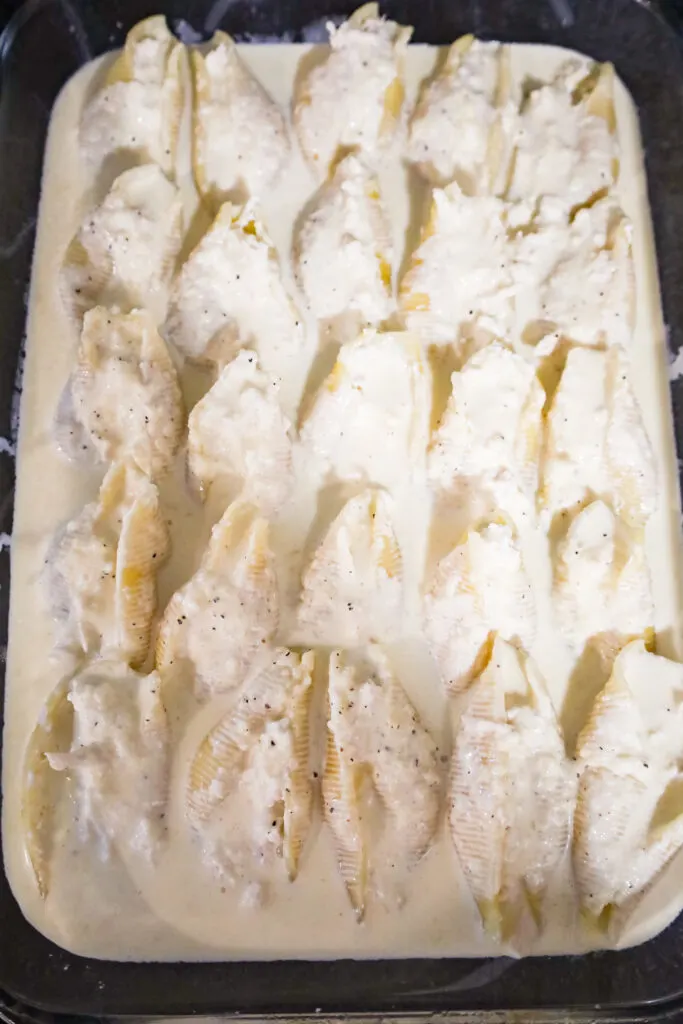 stuffed pasta shells in creamy alfredo sauce in a baking dish