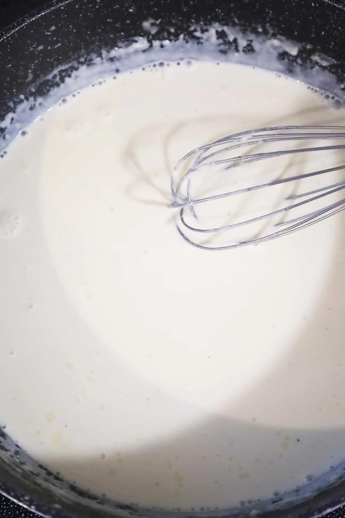 creamy alfredo sauce cooking in a pan