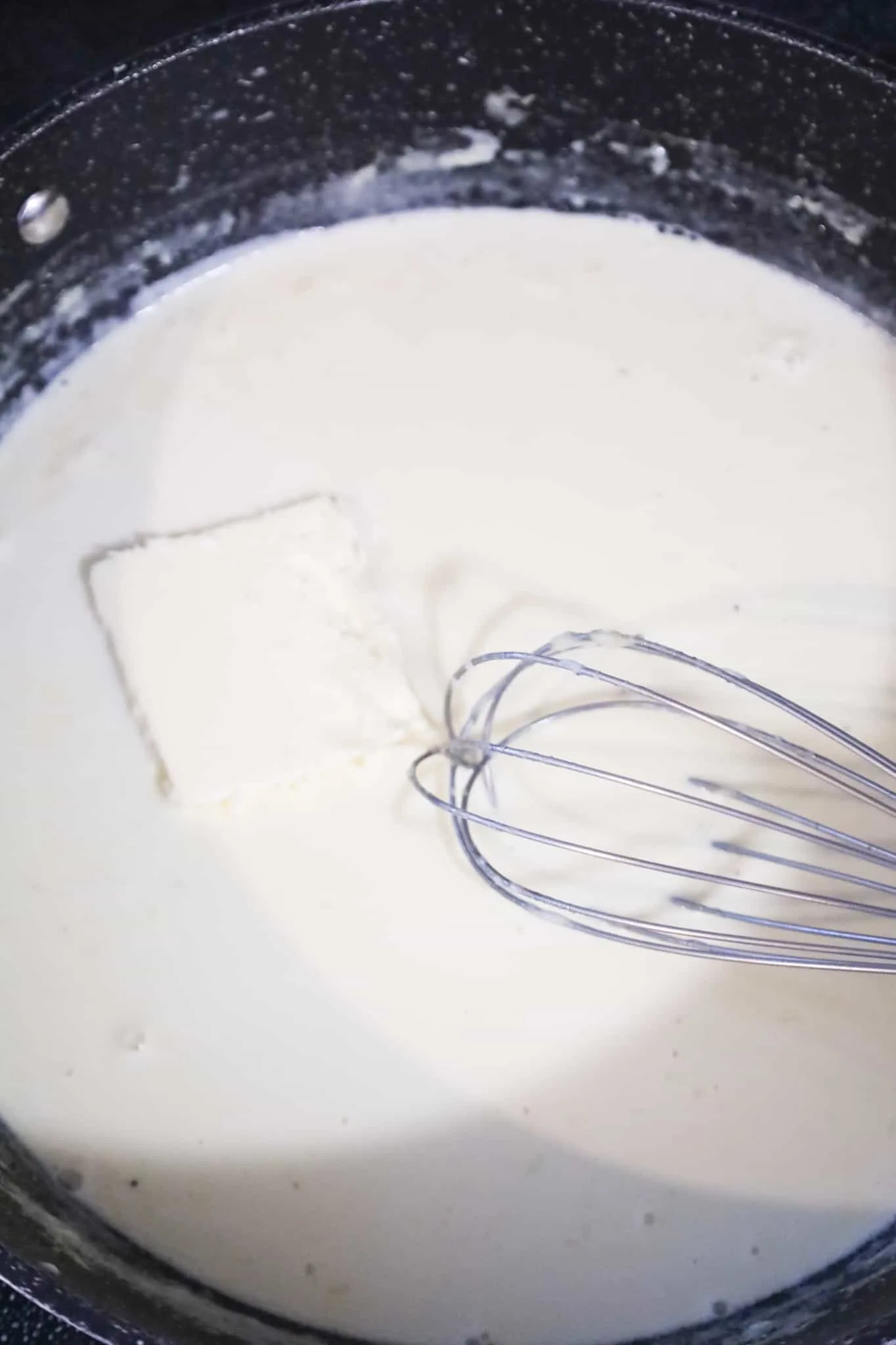 butter added to creamy alfredo sauce in a pan