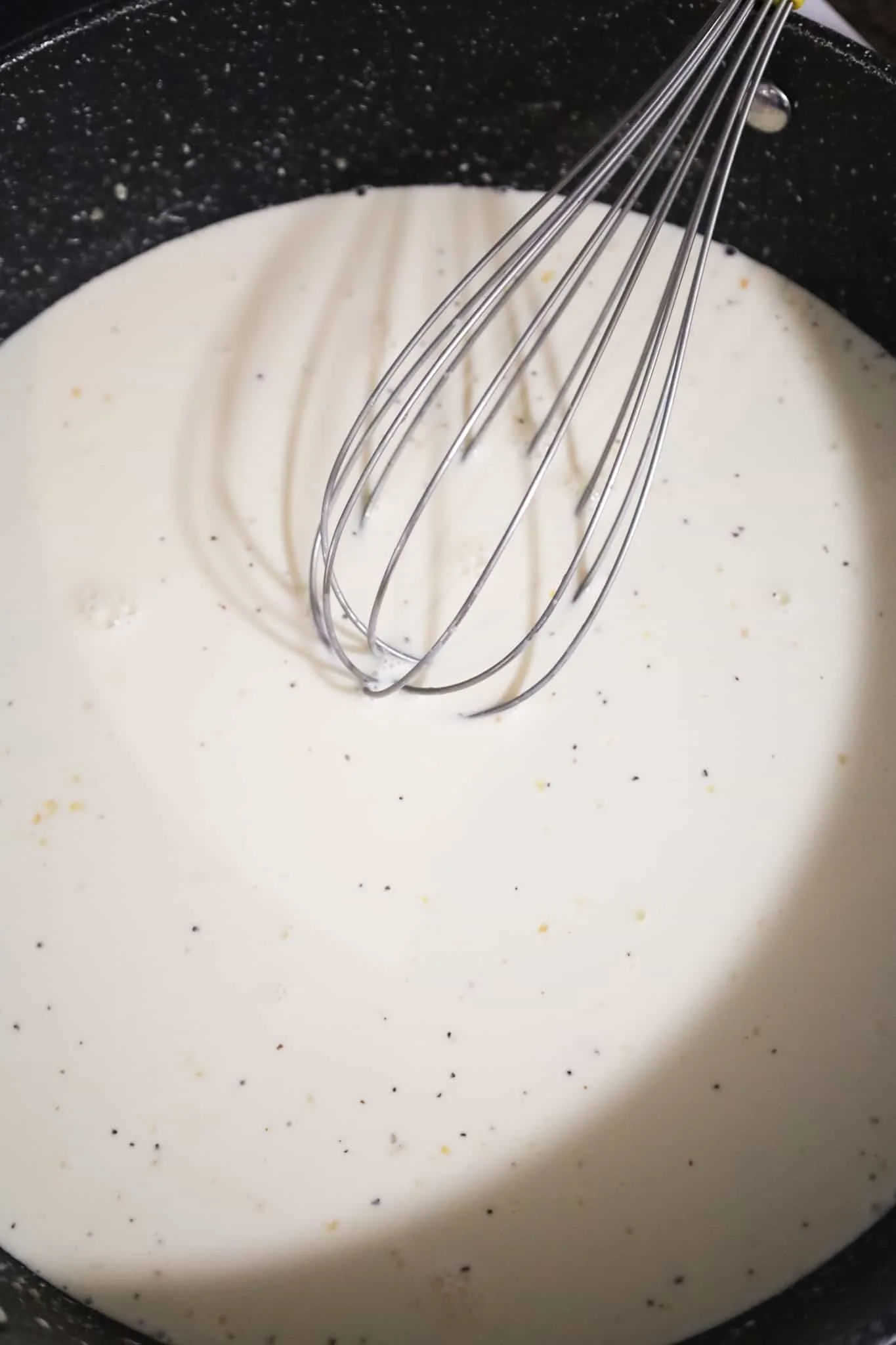 cream sauce being whisked in a pan