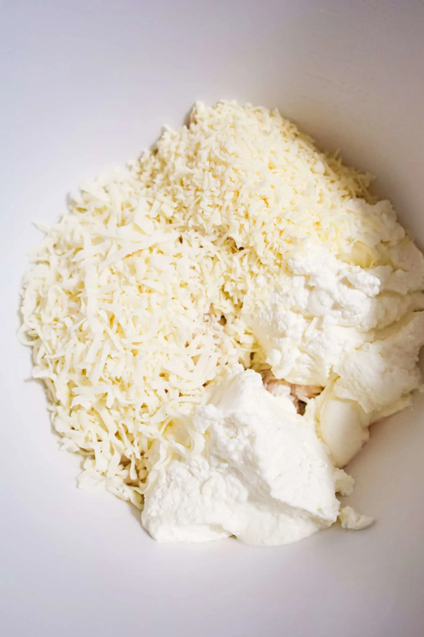 shredded parmesan, shredded mozzarella and ricotta in a mixing bowl