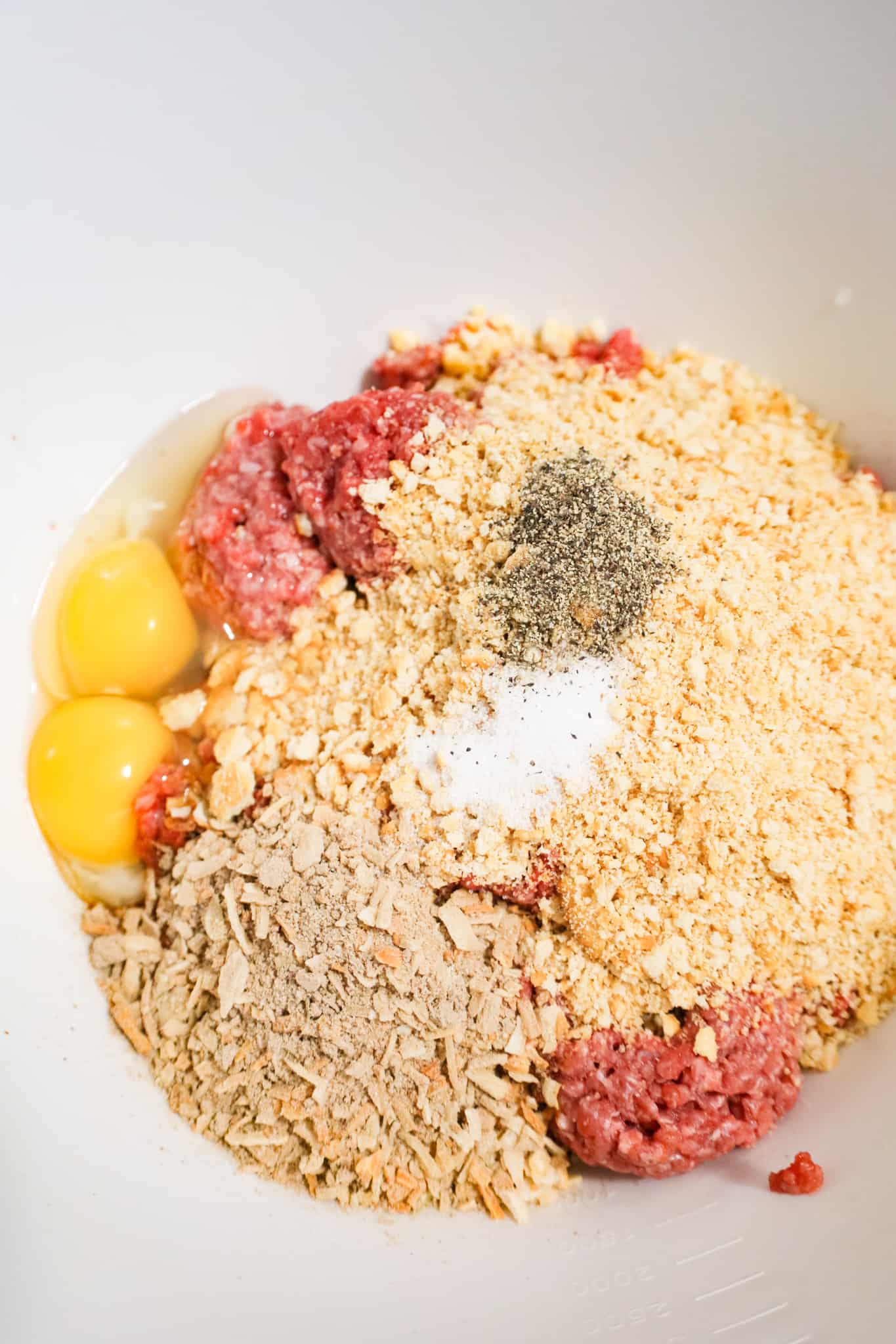 eggs, Lipton onion soup mix, crushed Ritz crackers and spices on top of raw ground beef in a mixing bowl