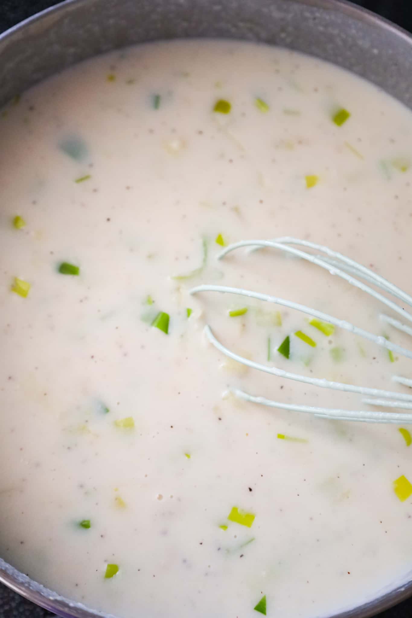 Whisking potato leek soup in a pot.