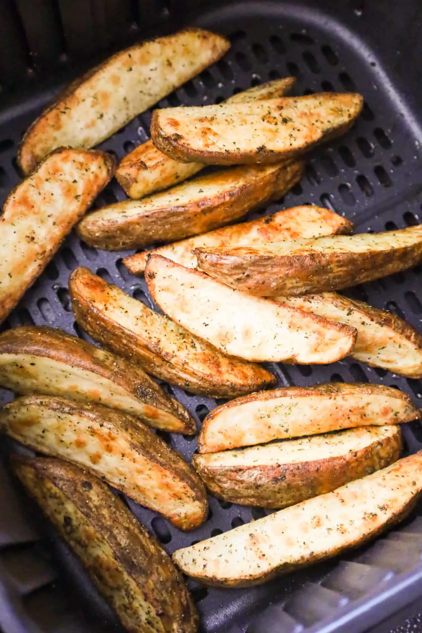 potato wedges in an air fryer basket after cooking