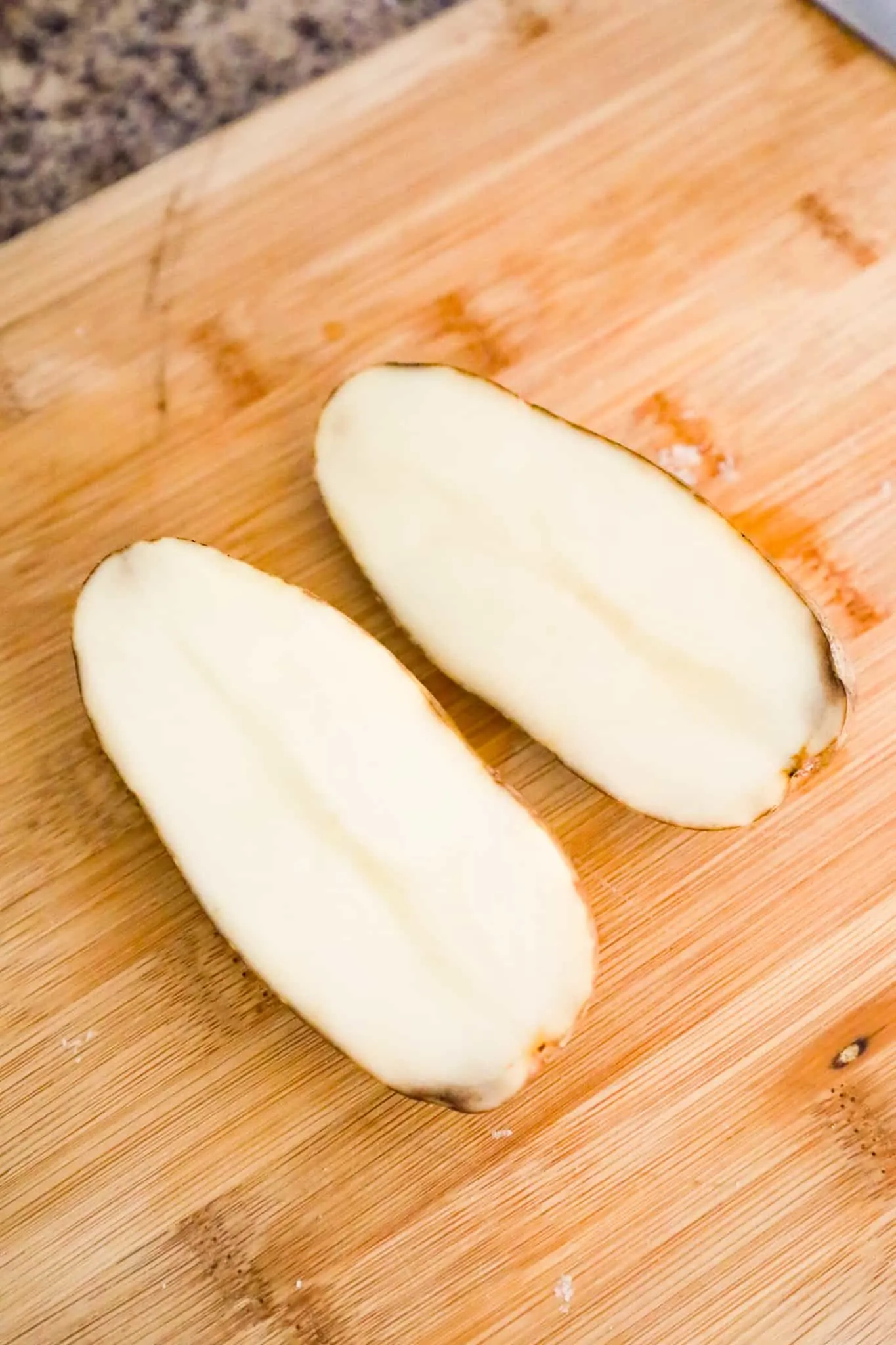 raw potato sliced in half on cutting board