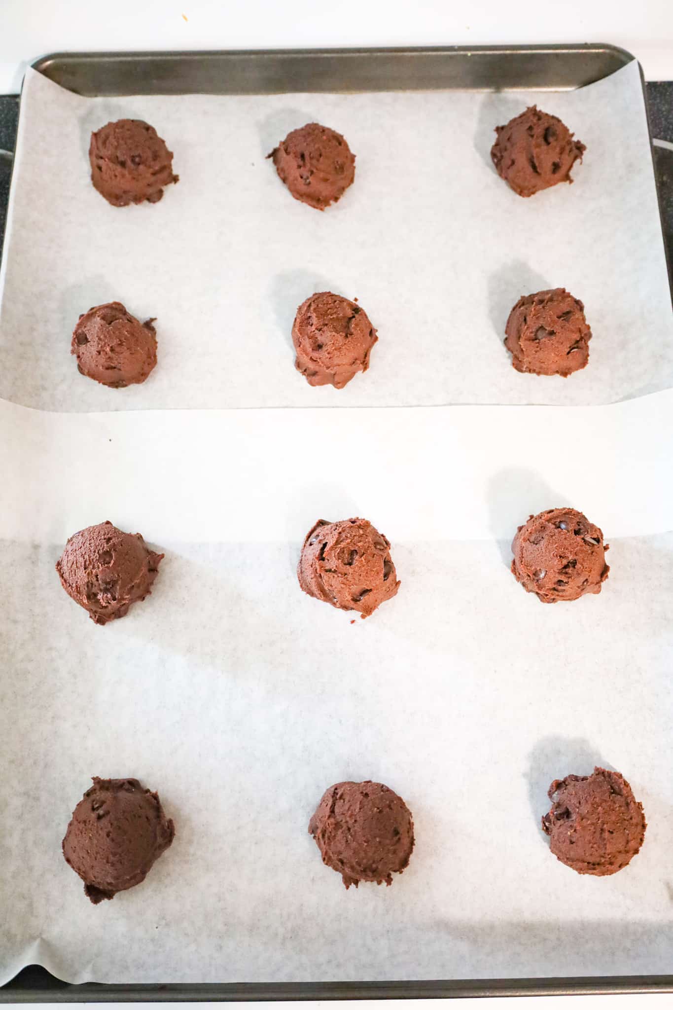 brownie mix cookie dough balls on a parchment lined baking sheet