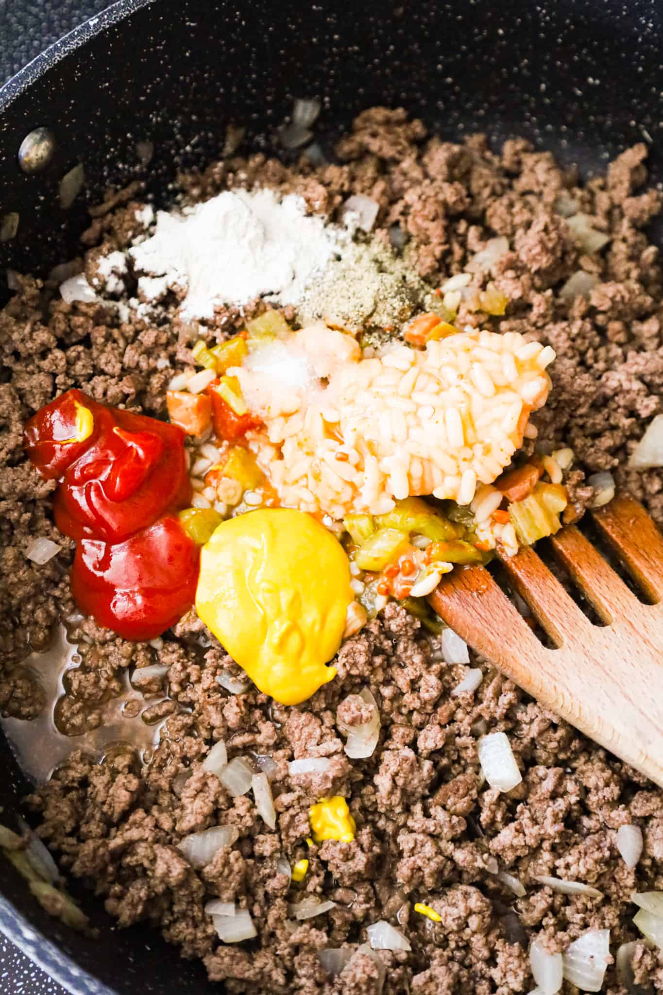 condensed chicken gumbo soup, ketchup, mustard and spices on top of cooked ground beef in a saute pan