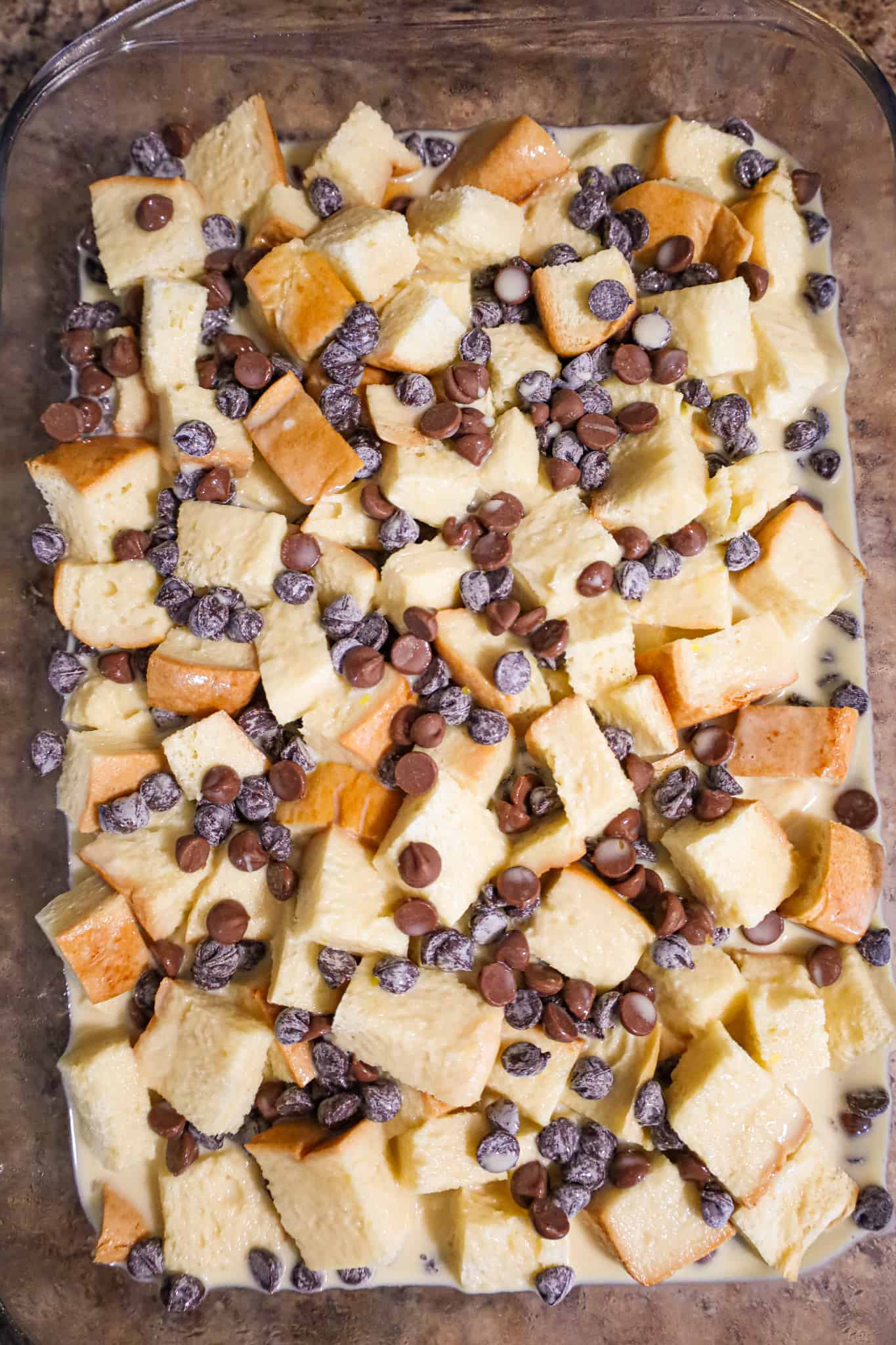 semi sweet and milk chocolate chips on top of cubed brioche bread in a baking dish with custard mixture