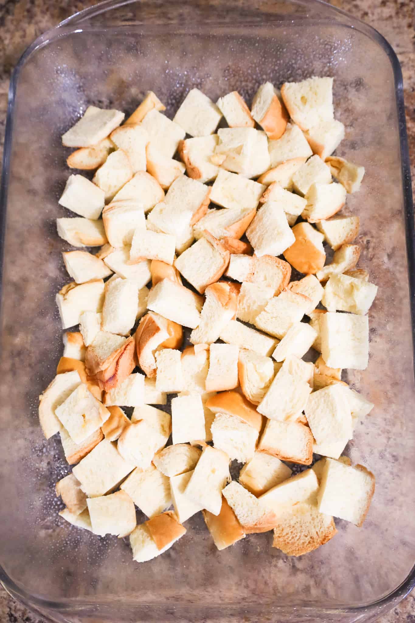 cubed brioche bread in the bottom of a baking dish