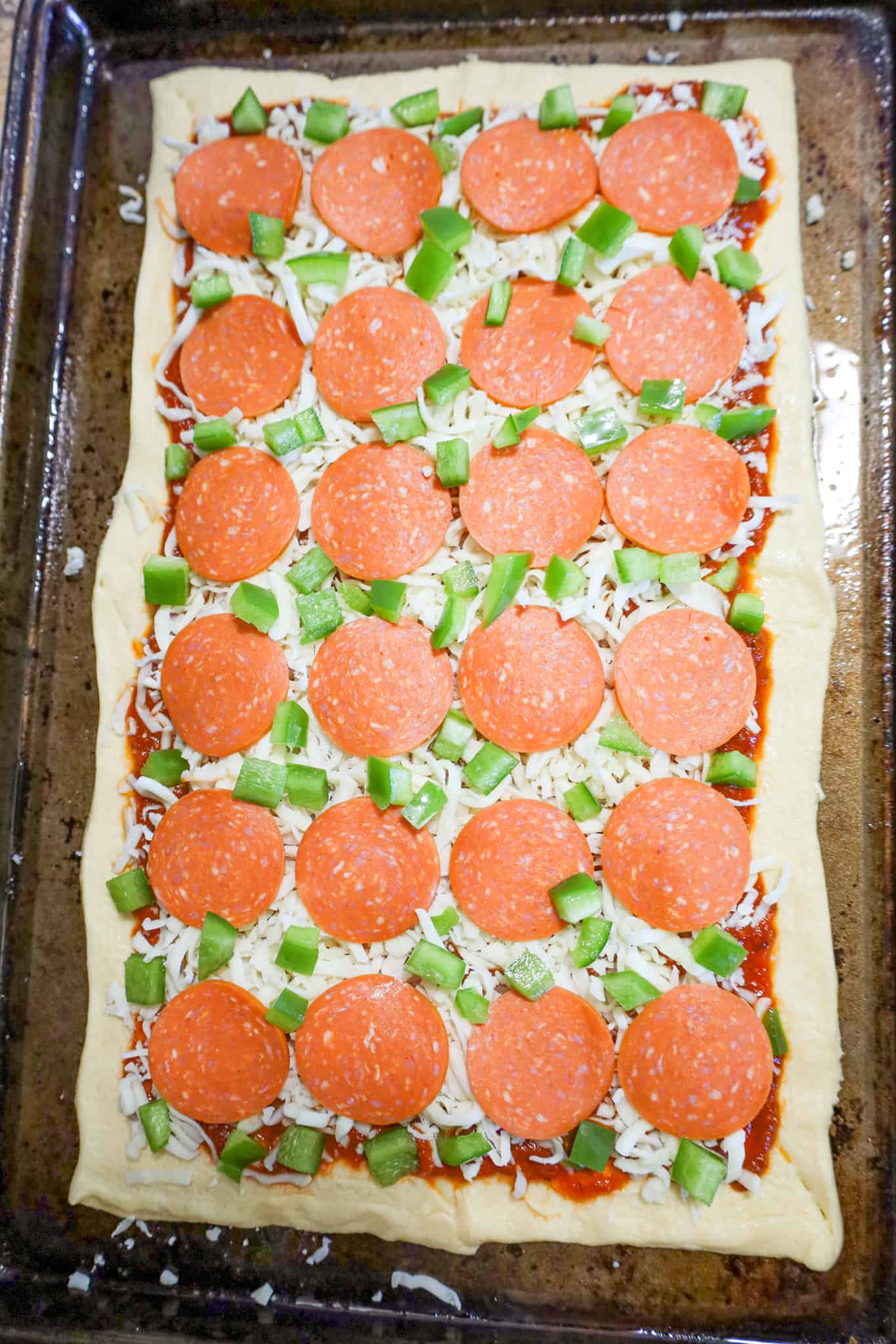 diced green peppers, pepperoni slices and shredded mozzarella cheese on top of crescent roll dough