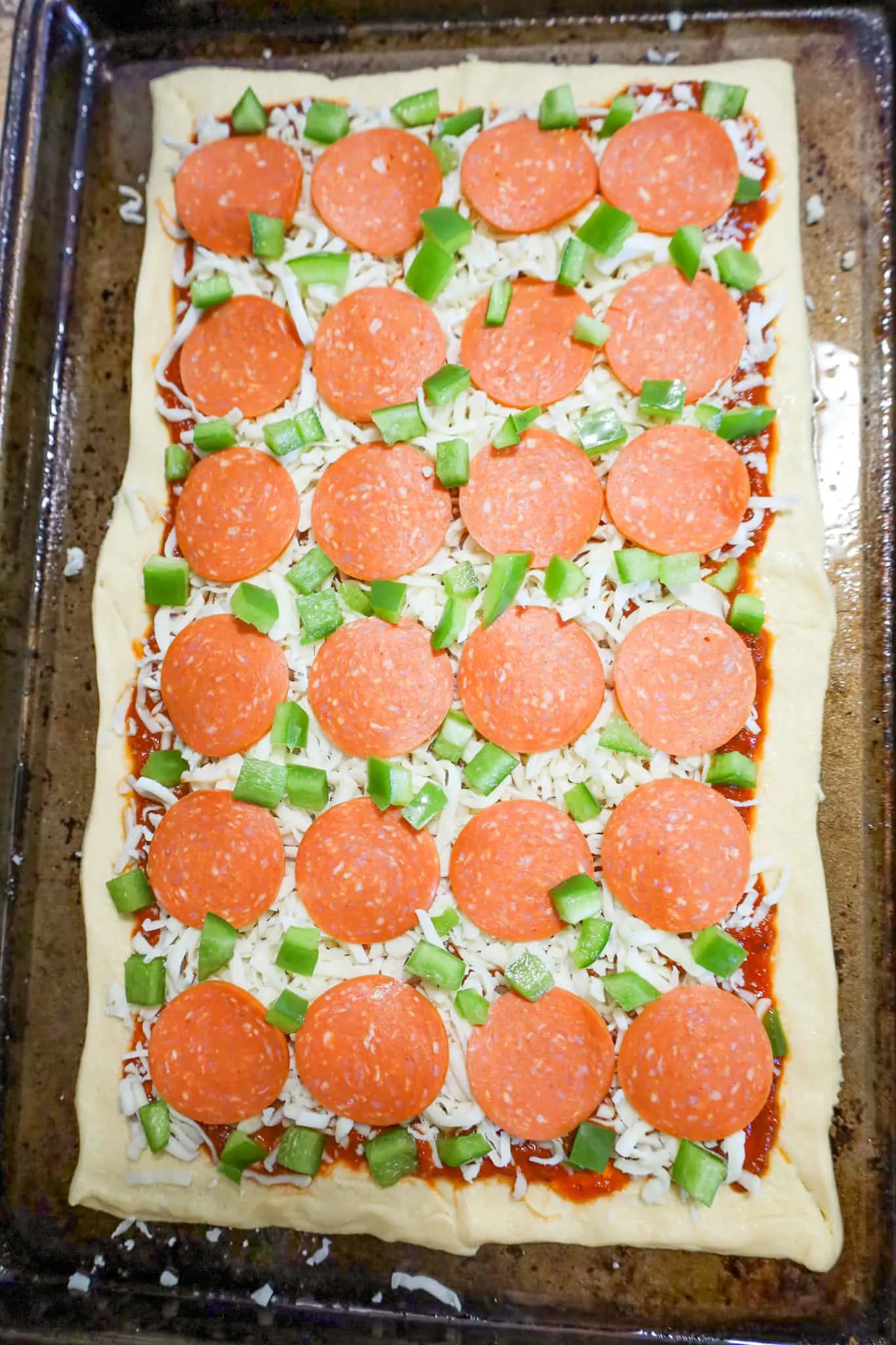 diced green peppers, pepperoni slices and shredded mozzarella cheese on top of crescent roll dough