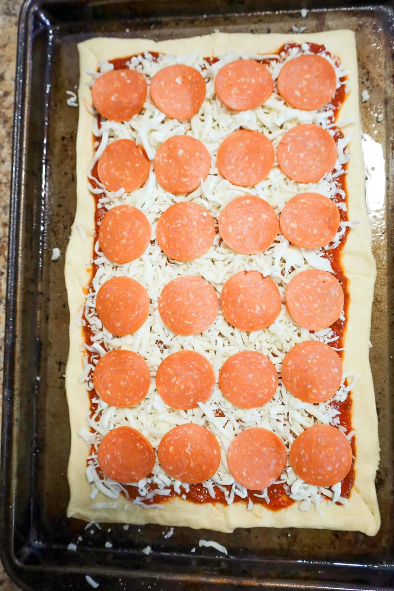 pepperoni slices and shredded cheese on top of sheet of pillsbury crescent dough