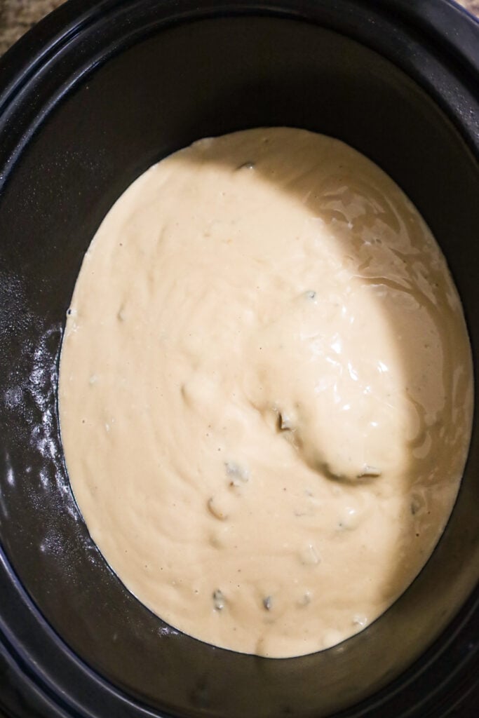 cream of mushroom soup and beef broth mixture poured over ground beef patties in a crock pot