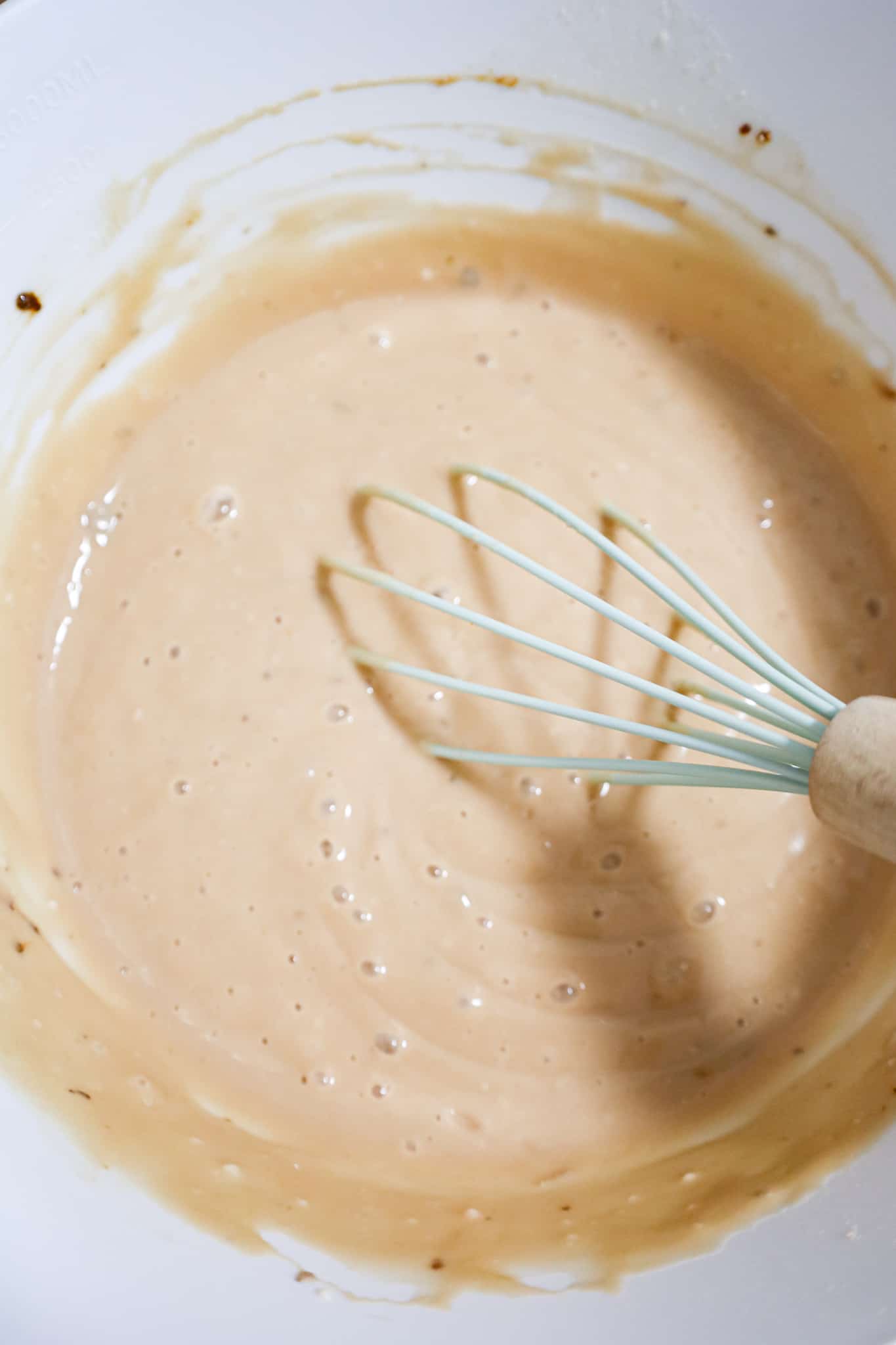 whisking together condensed cream of mushroom soup and beef broth in a mixing bowl