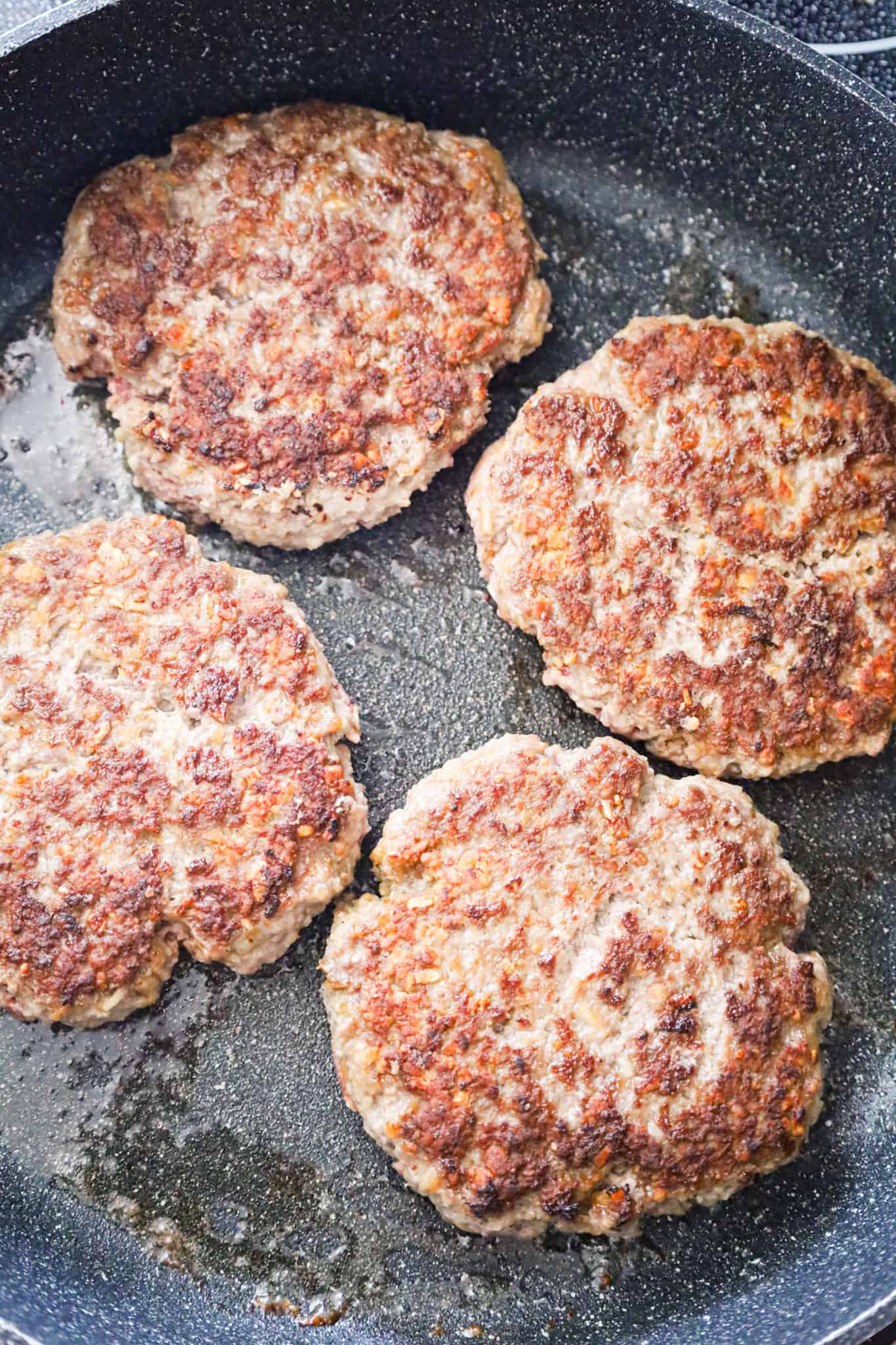 browned ground beef patties in a saute pan