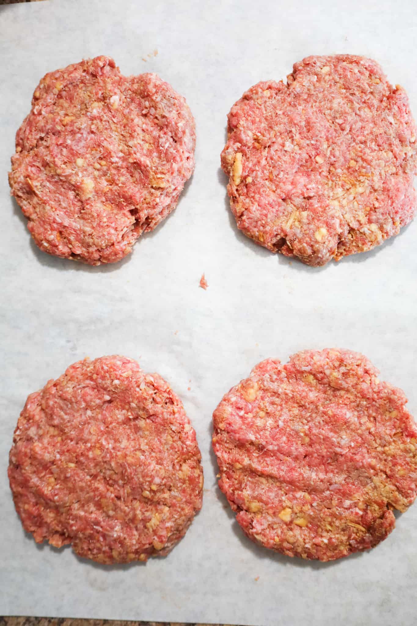 raw ground beef patties on parchment paper