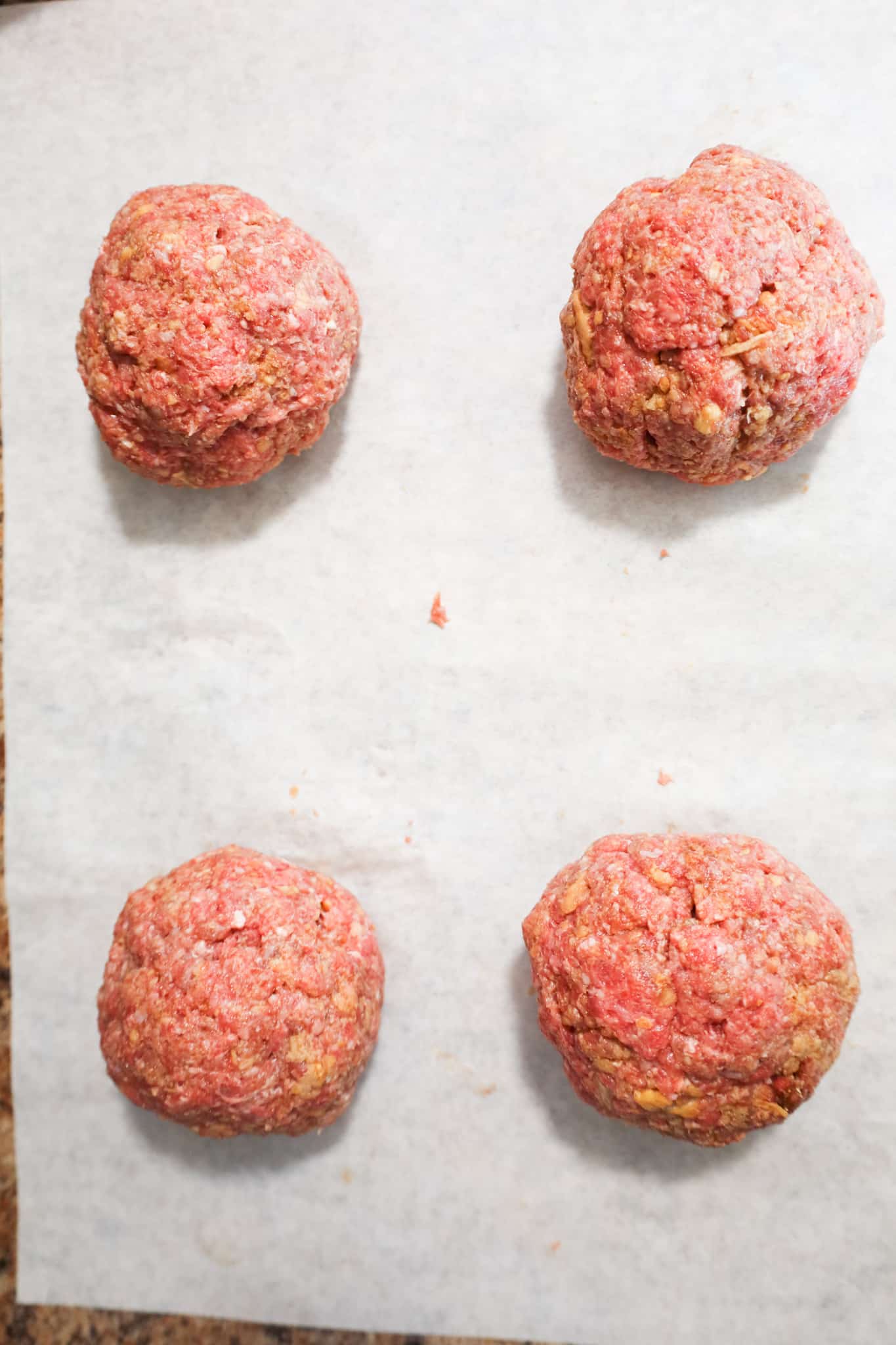 raw ground beef balls on parchment paper