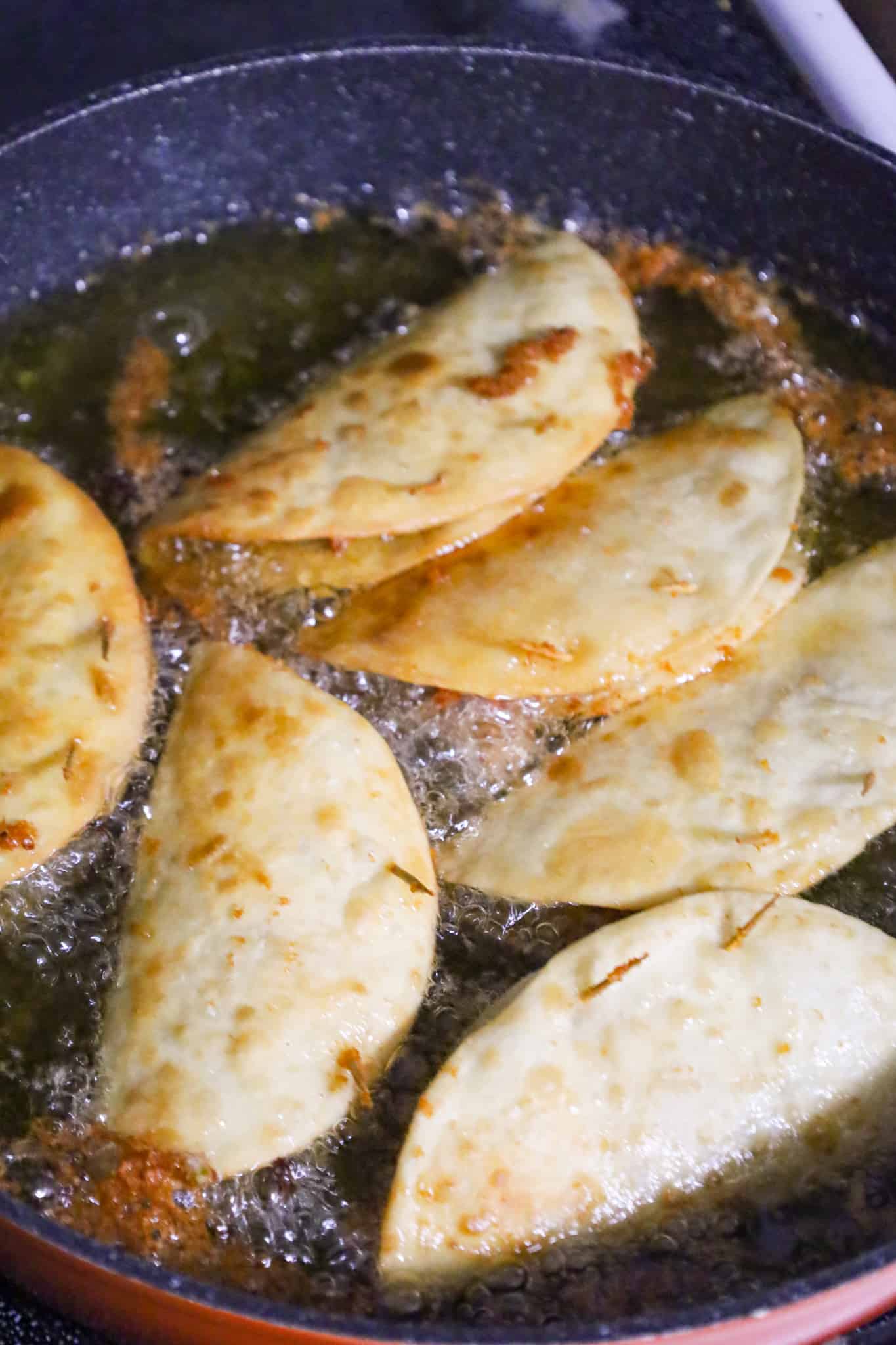 beef tacos frying in oil in a saute pan