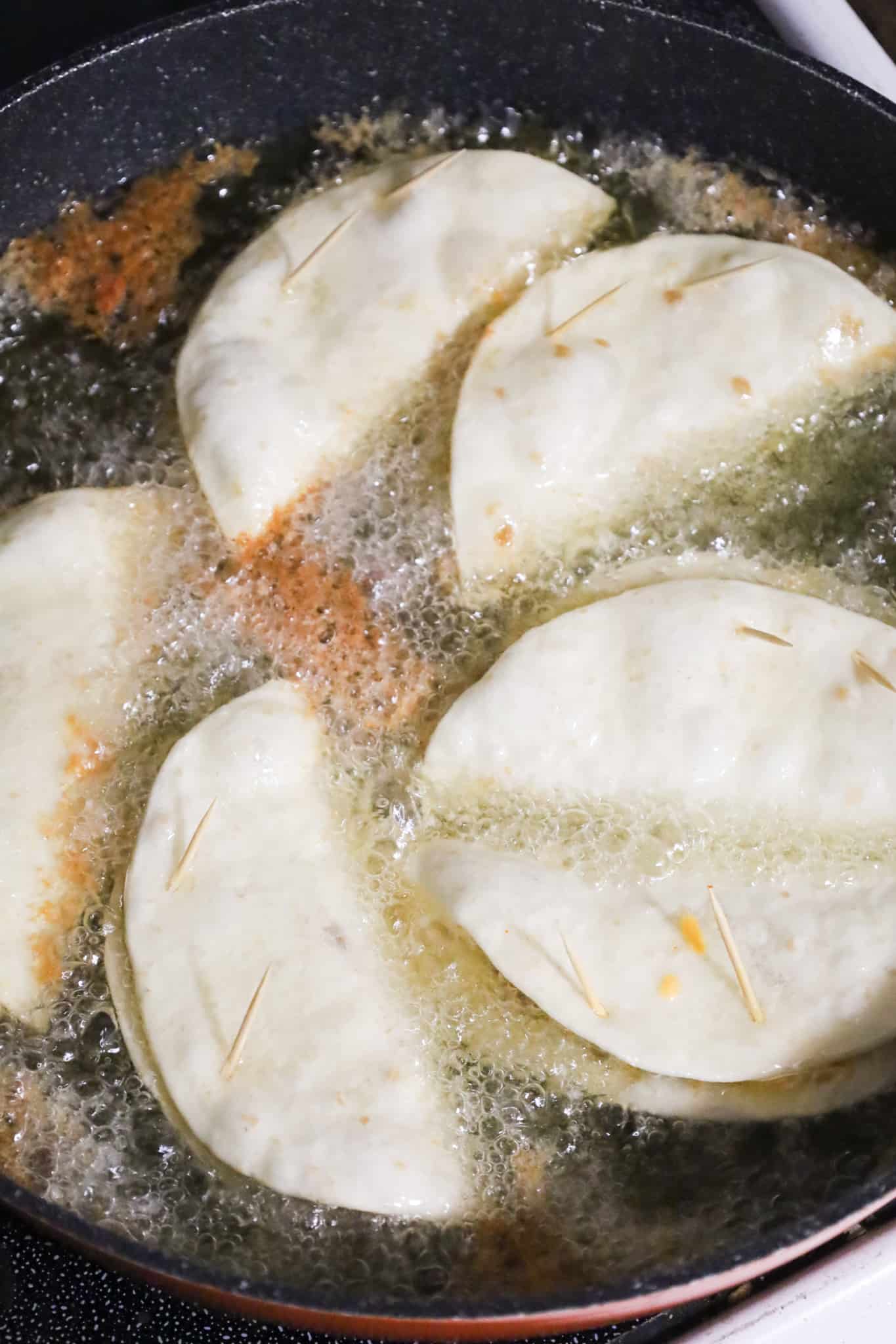 flour tortilla tacos frying in a skillet