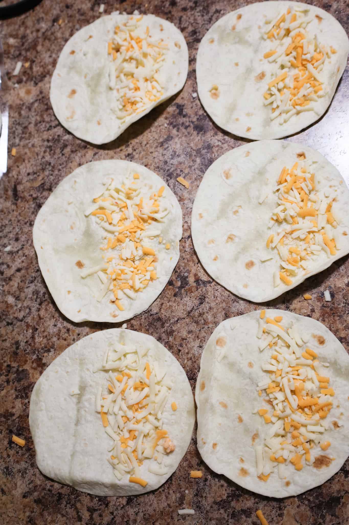 flour tortillas with shredded cheese on half