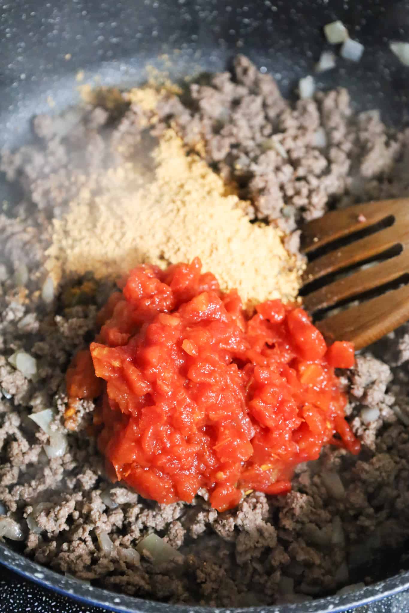 taco seasoning and Rotel on top of cooked ground beef in a saute pan