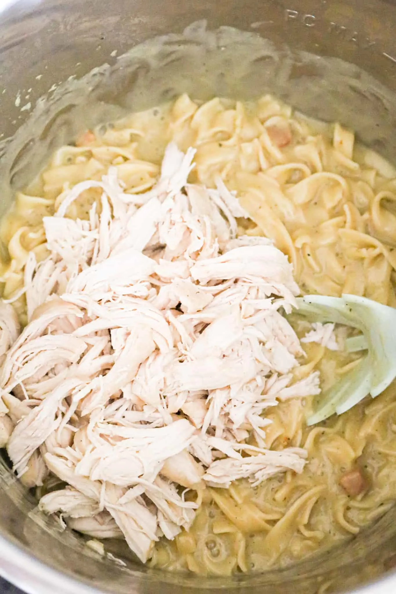 shredded chicken breast on top of creamy egg noodle mixture in an Instant Pot