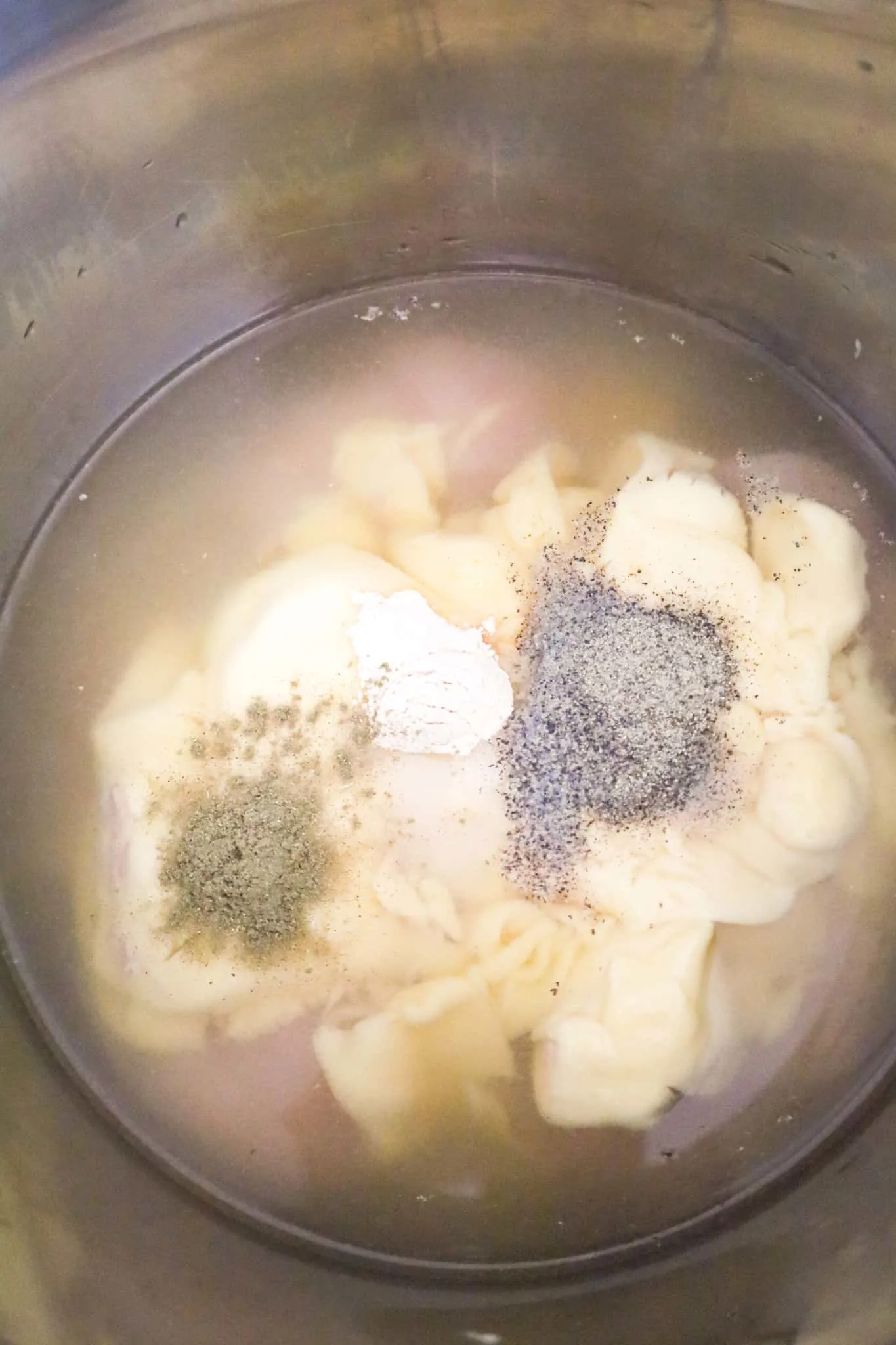 spices and cream of chicken soup on top of raw chicken breasts in an Instant Pot