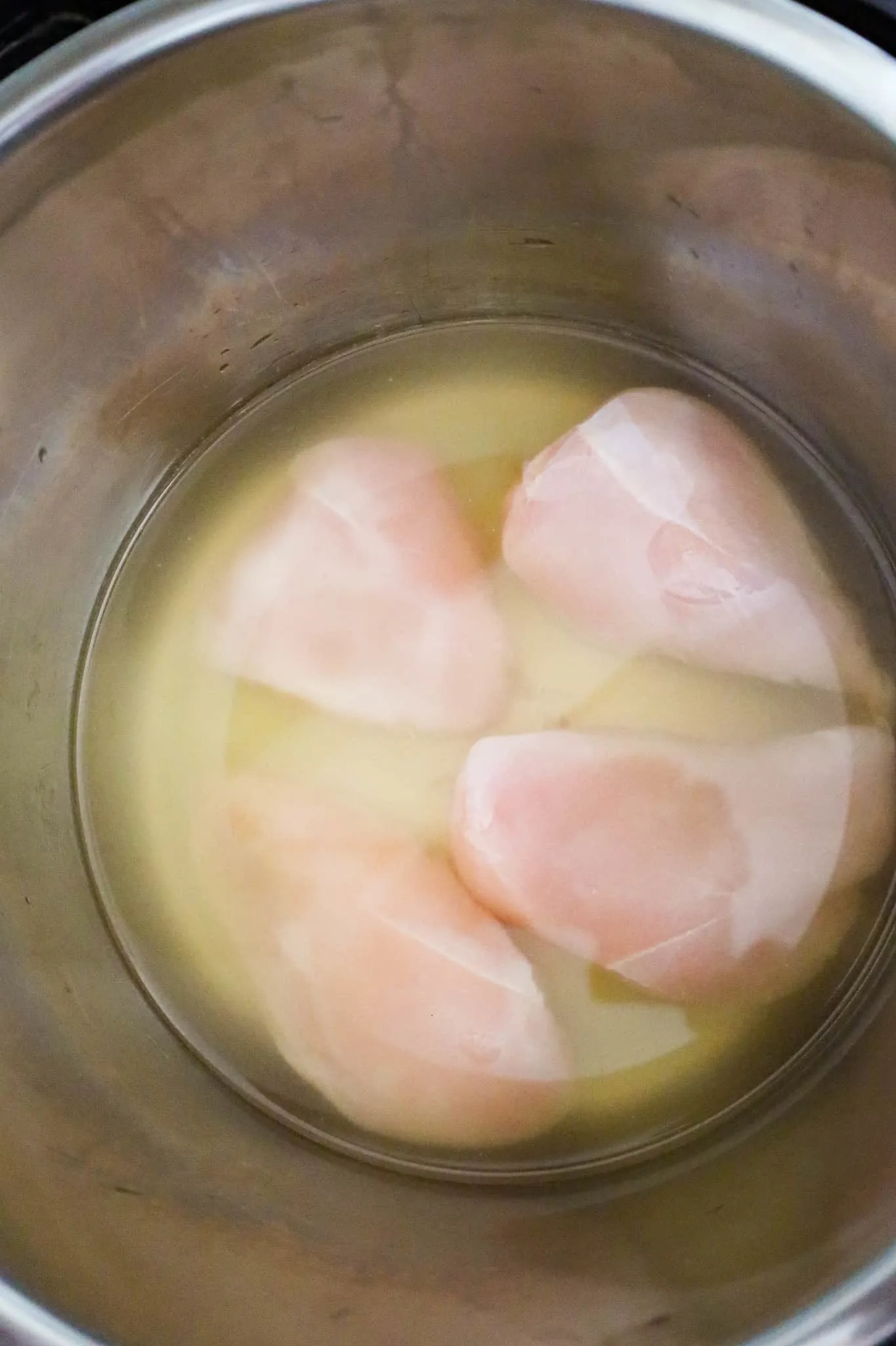 raw chicken breasts and chicken broth in an Instant Pot
