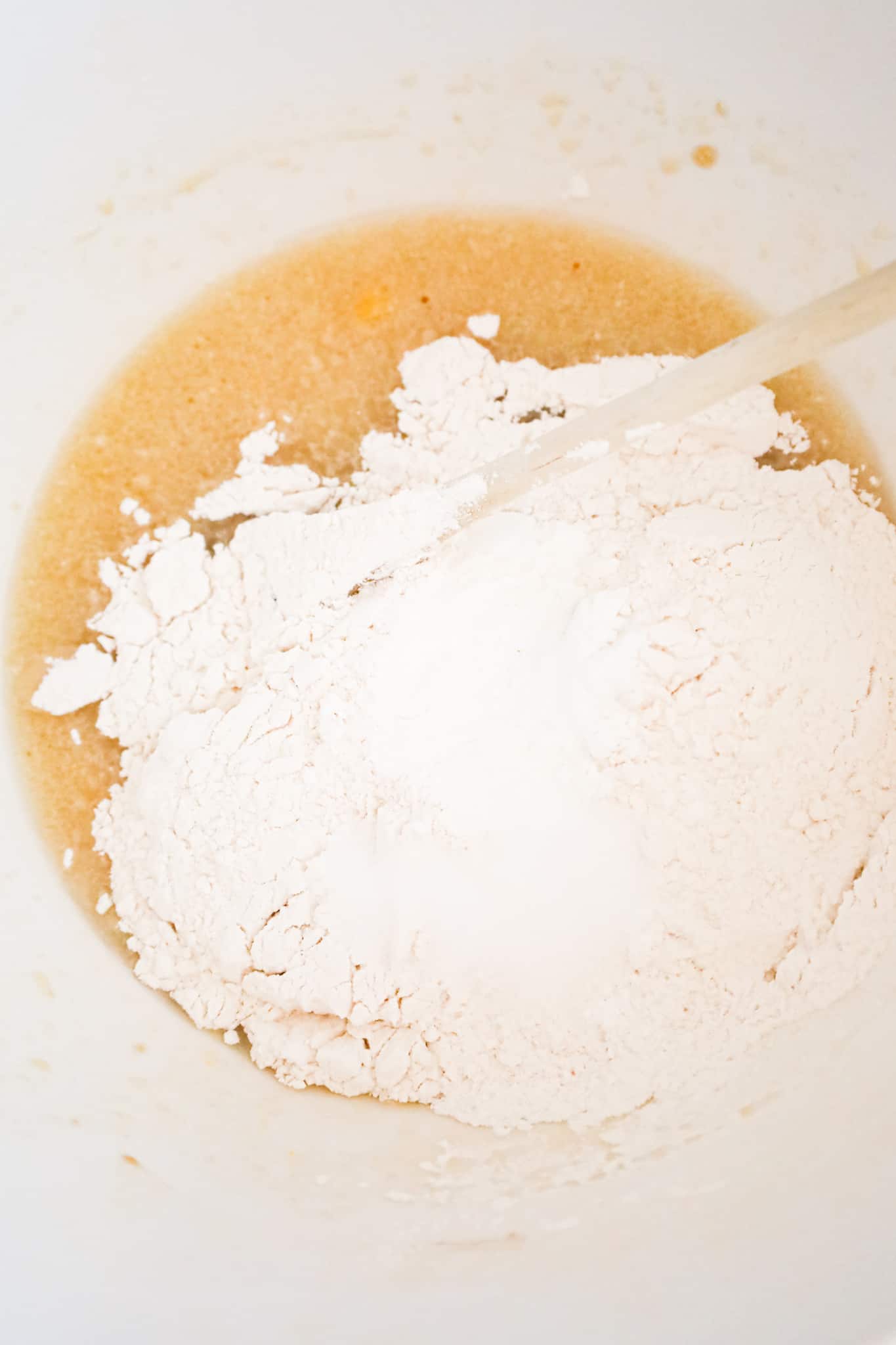 all purpose flour on top of liquid mixture in a mixing bowl