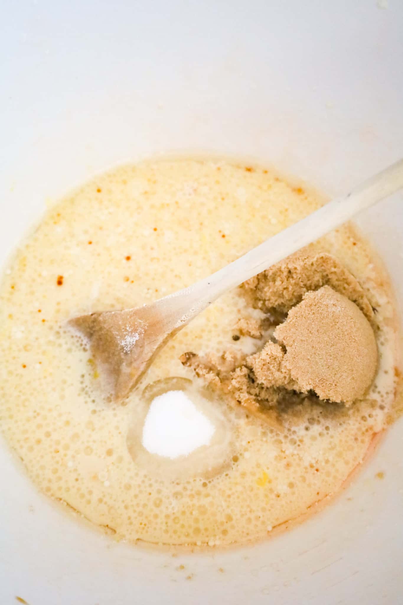 brown sugar and granulated sugar added to milk and oil mixture in a mixing bowl