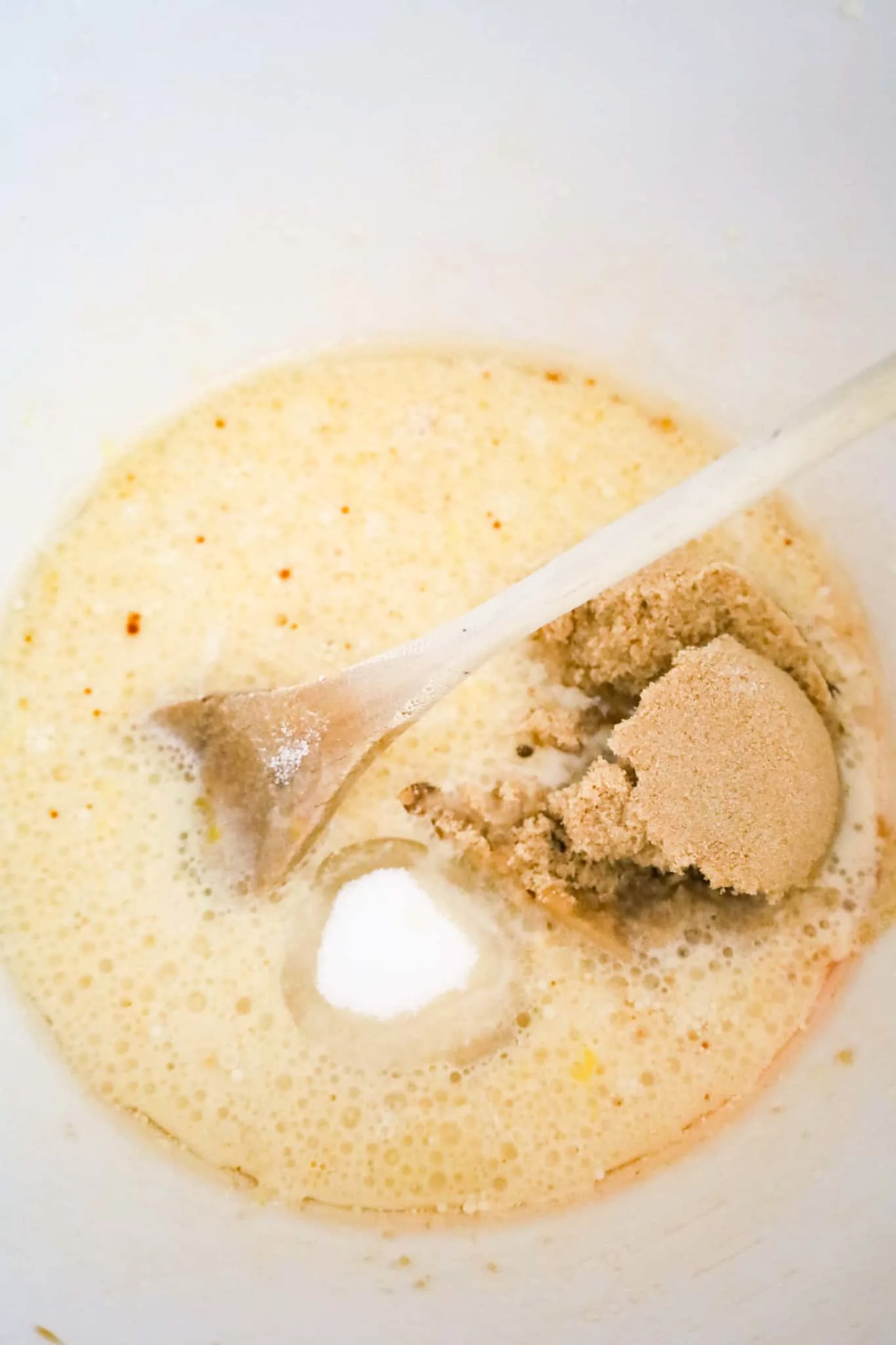 brown sugar and granulated sugar added to milk and oil mixture in a mixing bowl