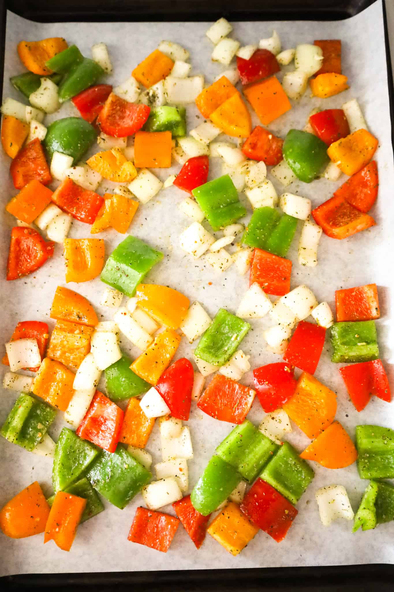 diced peppers and onions on a parchment lined baking sheet