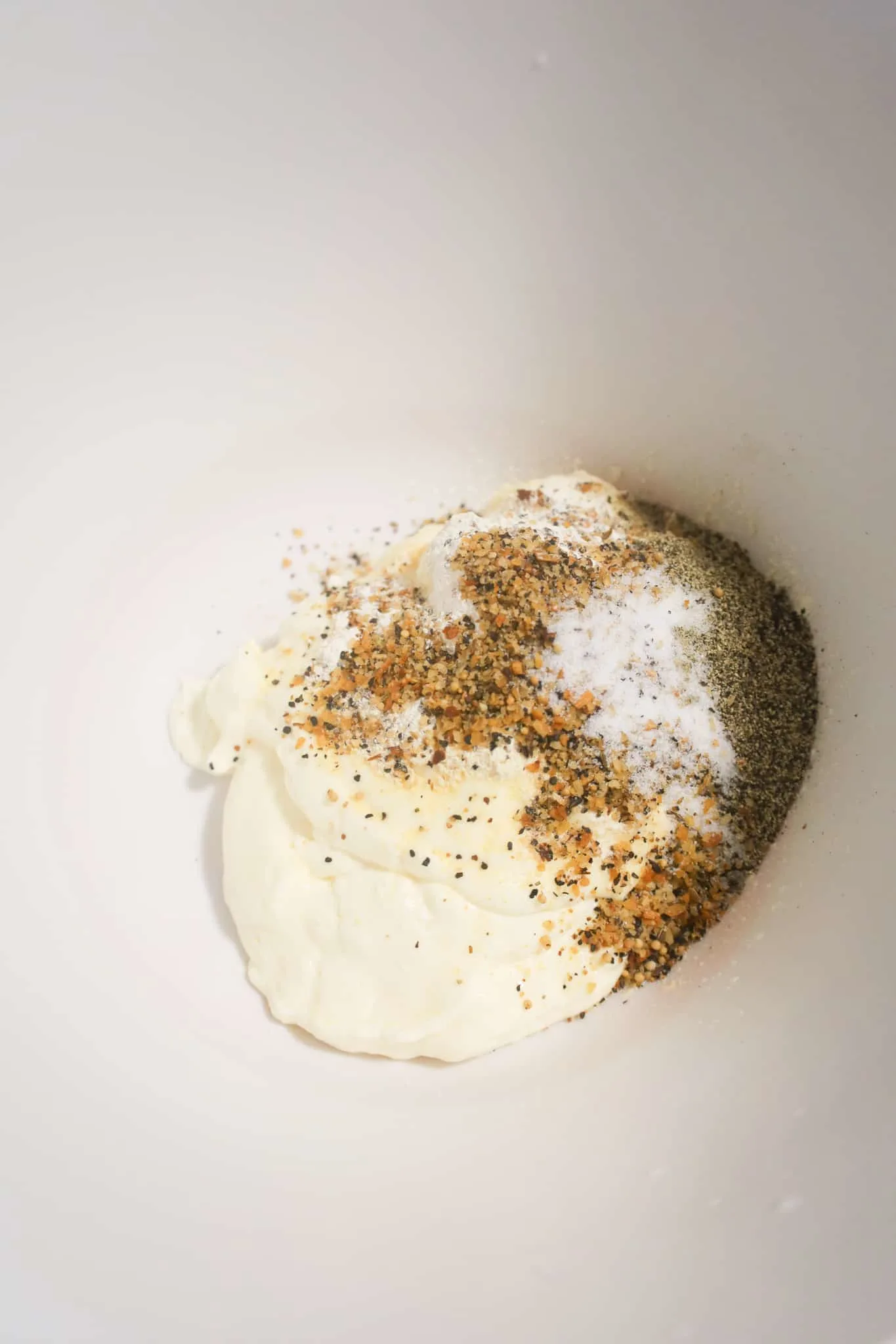 spices on top of mayo in a mixing bowl