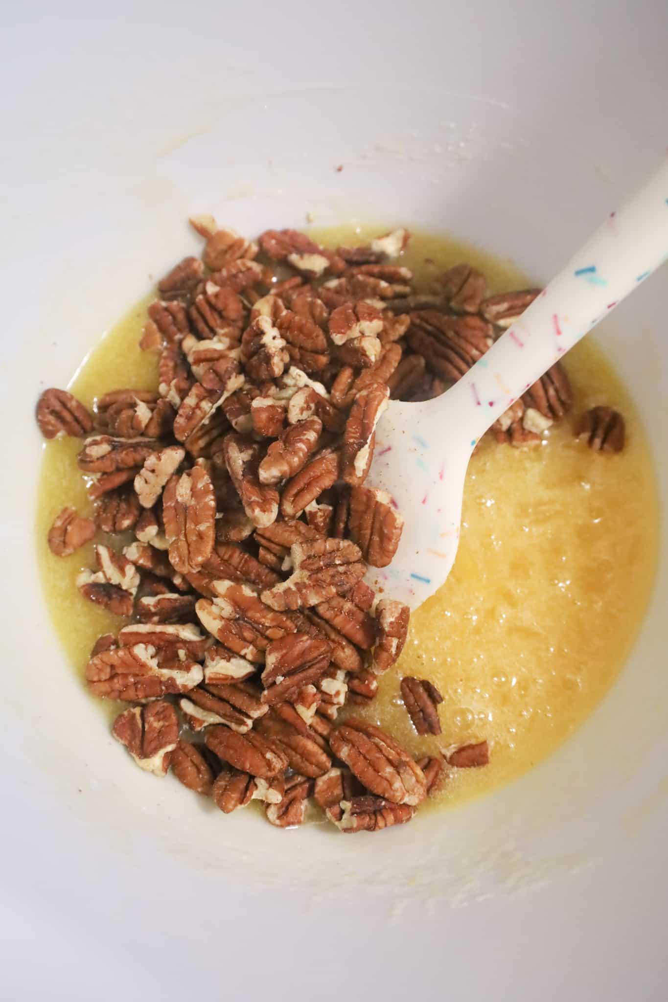 pecan halves on top of egg and sugar mixture in a mixing bowl