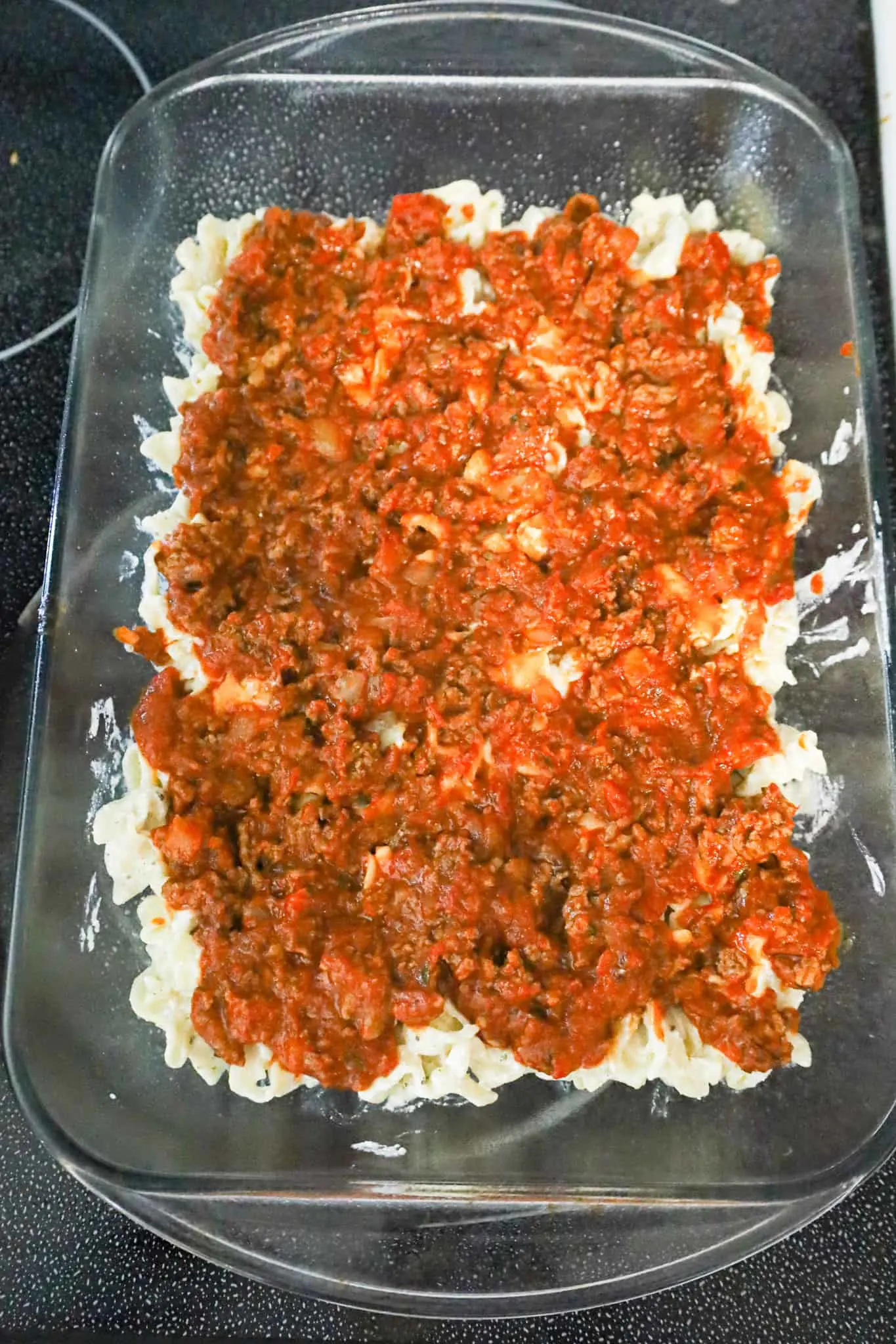 ground beef and marinara on top of sour cream noodle mixture in a baking dish