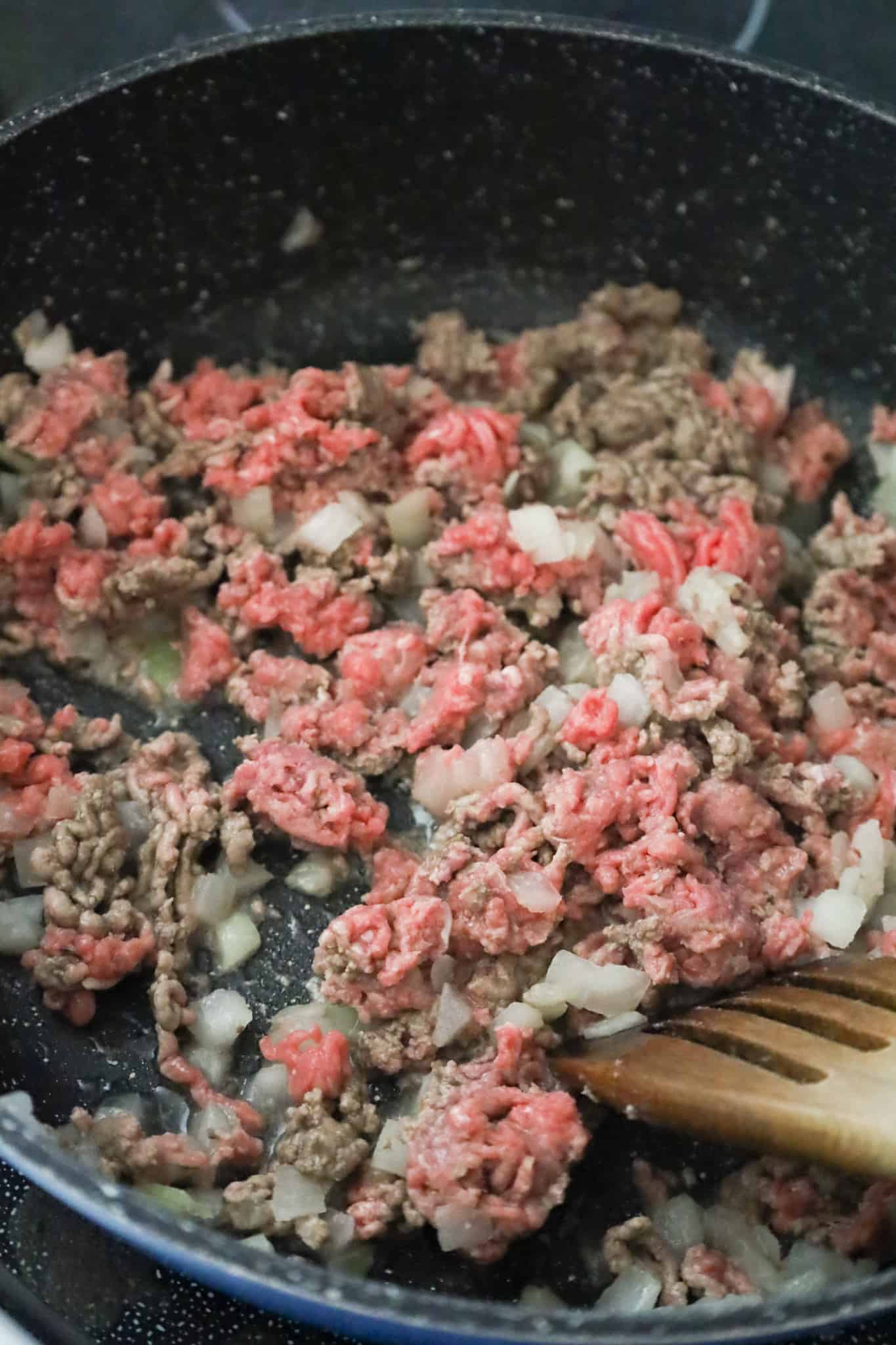 ground beef and diced onions cooking in a saute pan