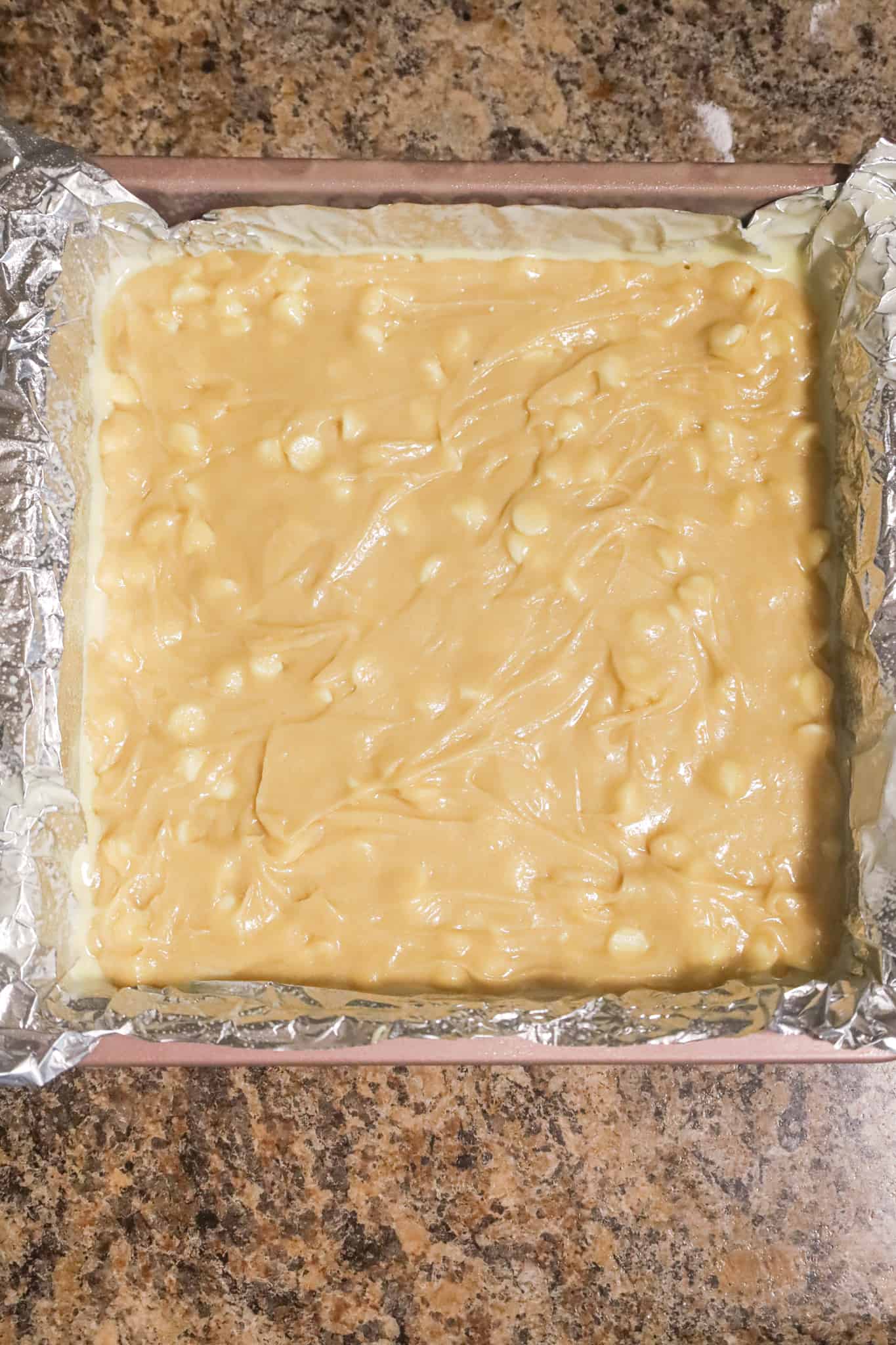 vanilla brownie batter in a foil lined baking pan