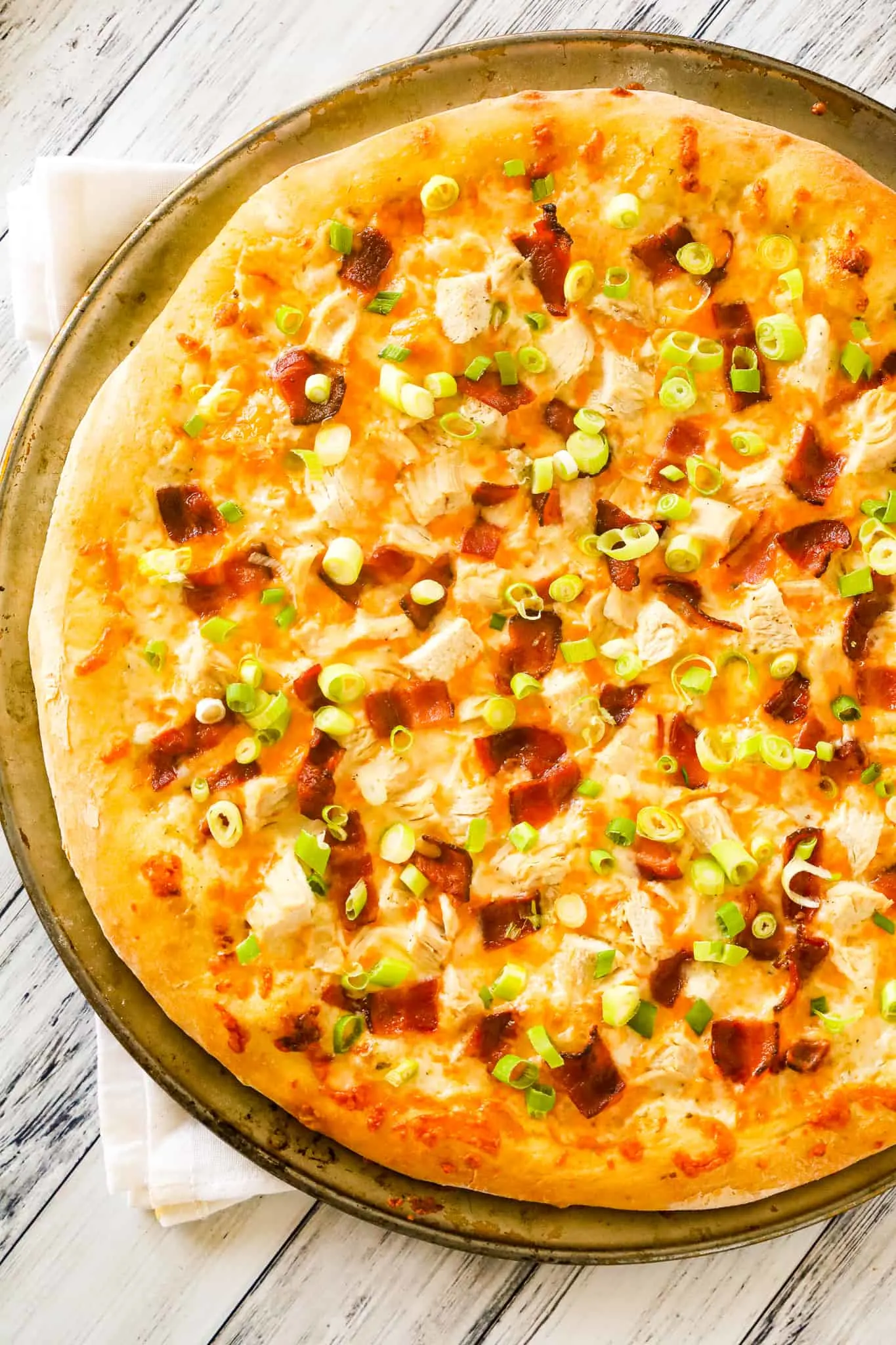 Chicken Bacon Ranch Pizza is an easy dinner recipe using store bought pizza dough loaded with ranch dressing, chicken breast chunks, bacon, chopped green onions and shredded mozzarella and cheddar cheese.