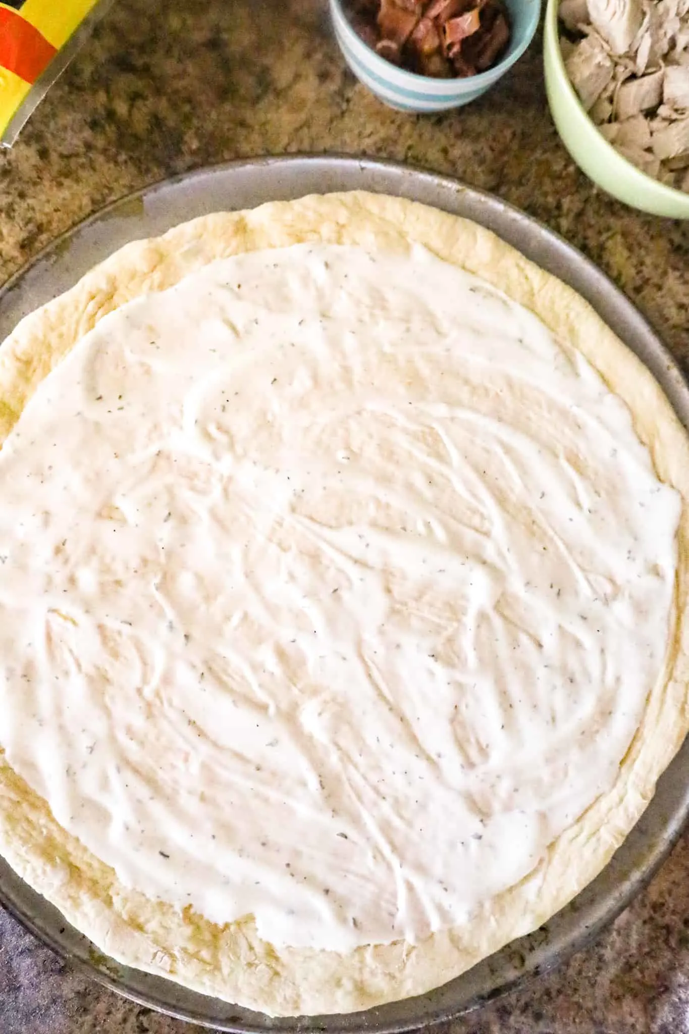 ranch dressing spread on pizza dough before baking