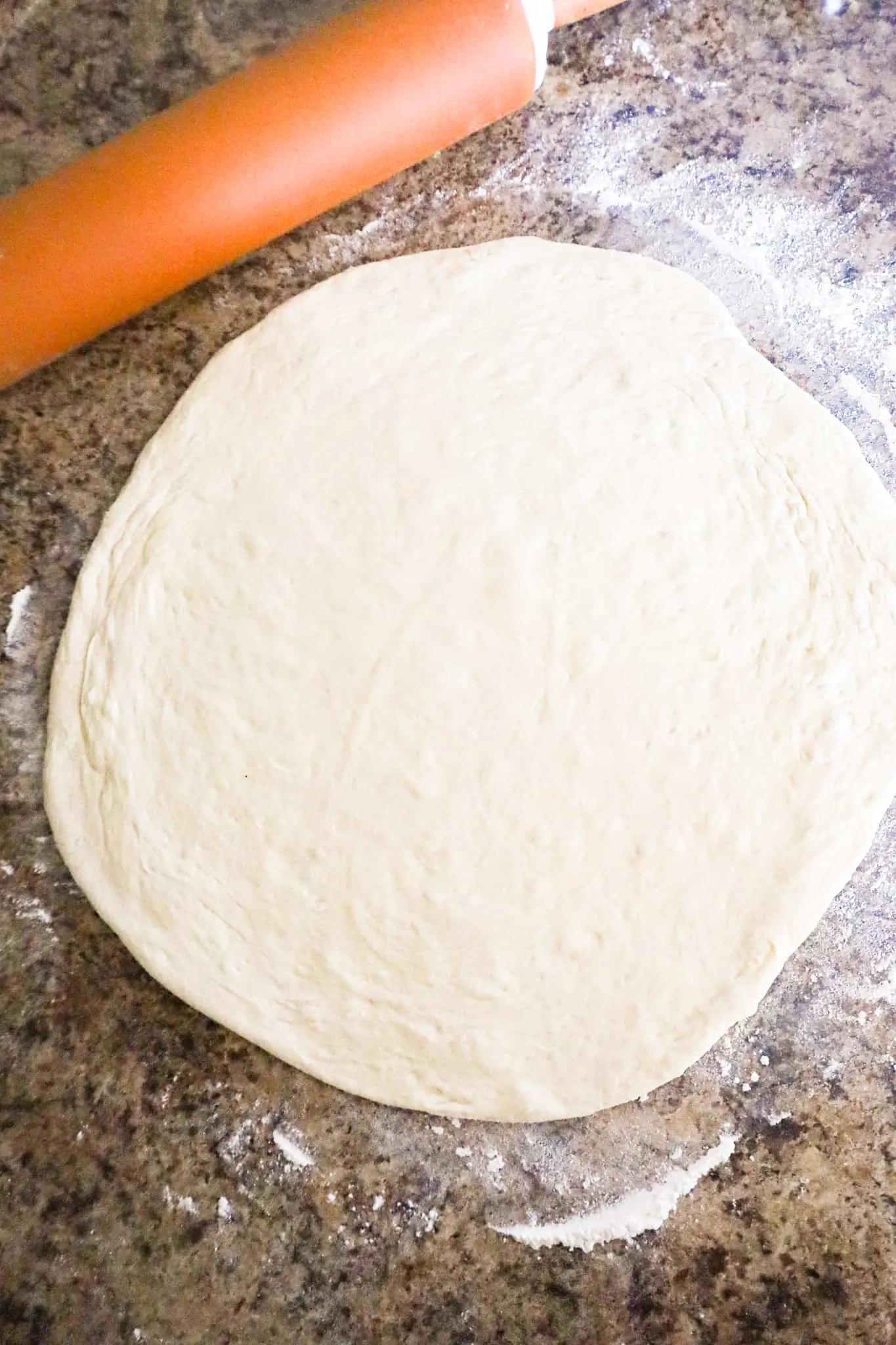 pizza dough rolled out in a circle