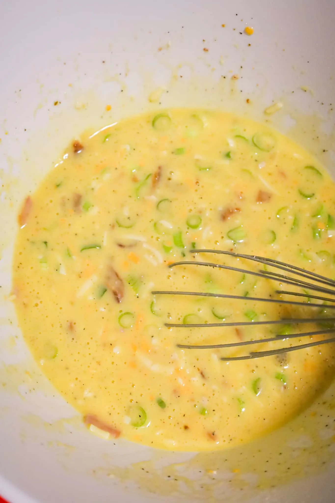 chopped green onions, chopped ham and shredded cheese whisked into egg mixture in a mixing bowl